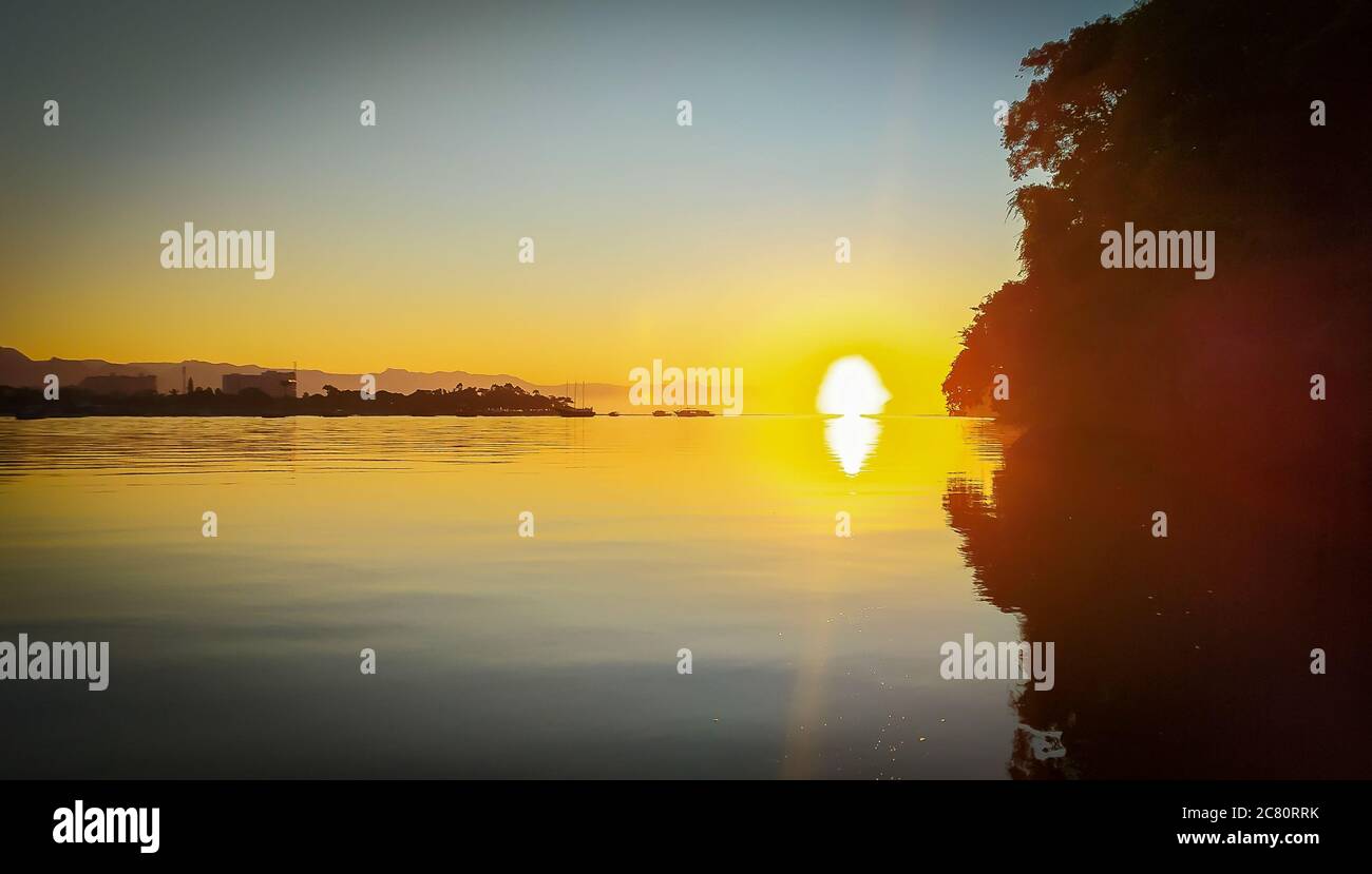 Sonnenaufgang Sonnenuntergang am Fluss 'Canal do estuário', zwischen den Städten Guaruja und Bertioga in Brasilien. Farbenfrohe und ruhige Sonnenaufgänge an einem ruhigen Fluss. Sli Stockfoto