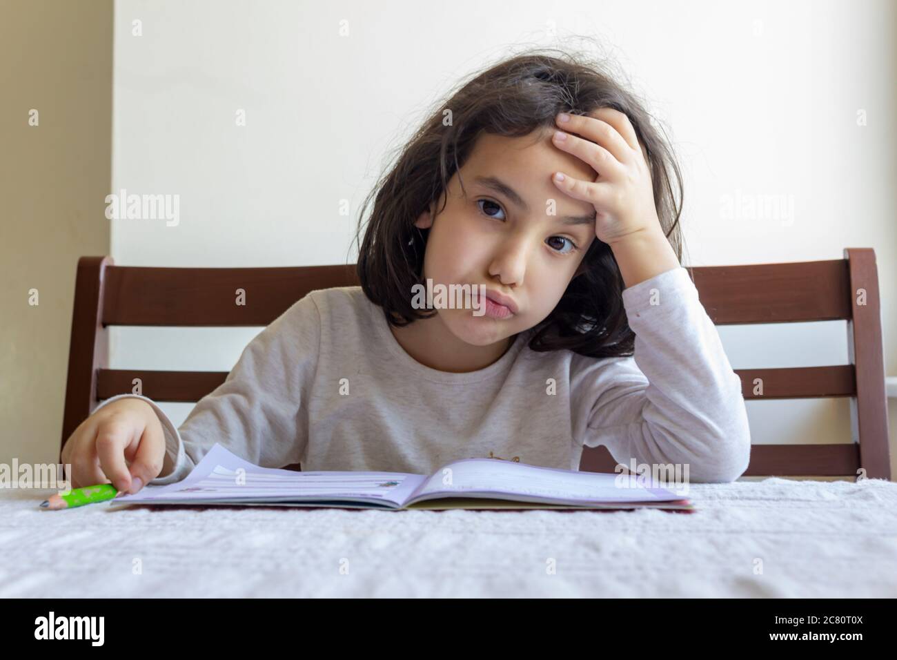 Grundschülerin macht ihre Hausaufgaben. Sie macht ihre eigenen Hausaufgaben allein zu Hause, weil die Schulen wegen der Corona pandemi geschlossen sind Stockfoto