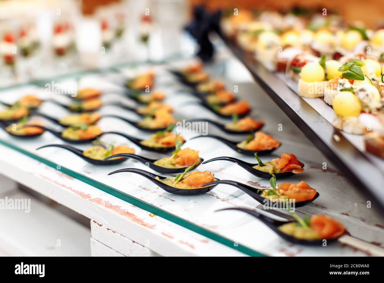 Verschiedene leichte Snacks auf Glas und Holztablett auf Hochzeitsfeier Stockfoto