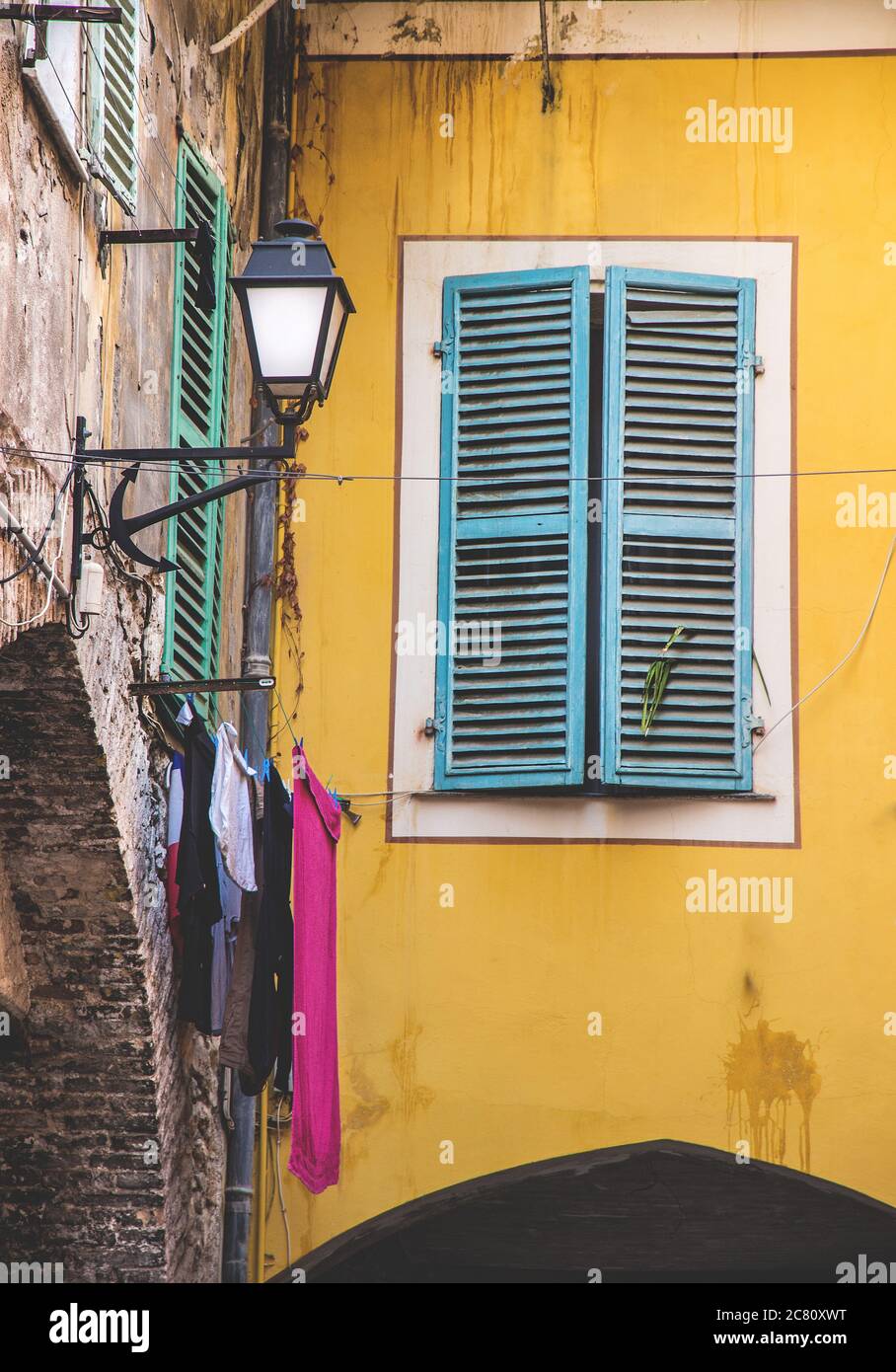 Die vertikale Aufnahme des blauen hölzernen Fensters auf dem gelben Gebäude in Itlay gefangen genommen Stockfoto