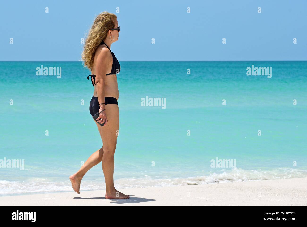 HOLMES BEACH, ANNA MARIA ISLAND, FL / USA - 1. Mai 2018: Schöne reife Frau bei einem Spaziergang am Strand und einem schönen Sommertag. Stockfoto
