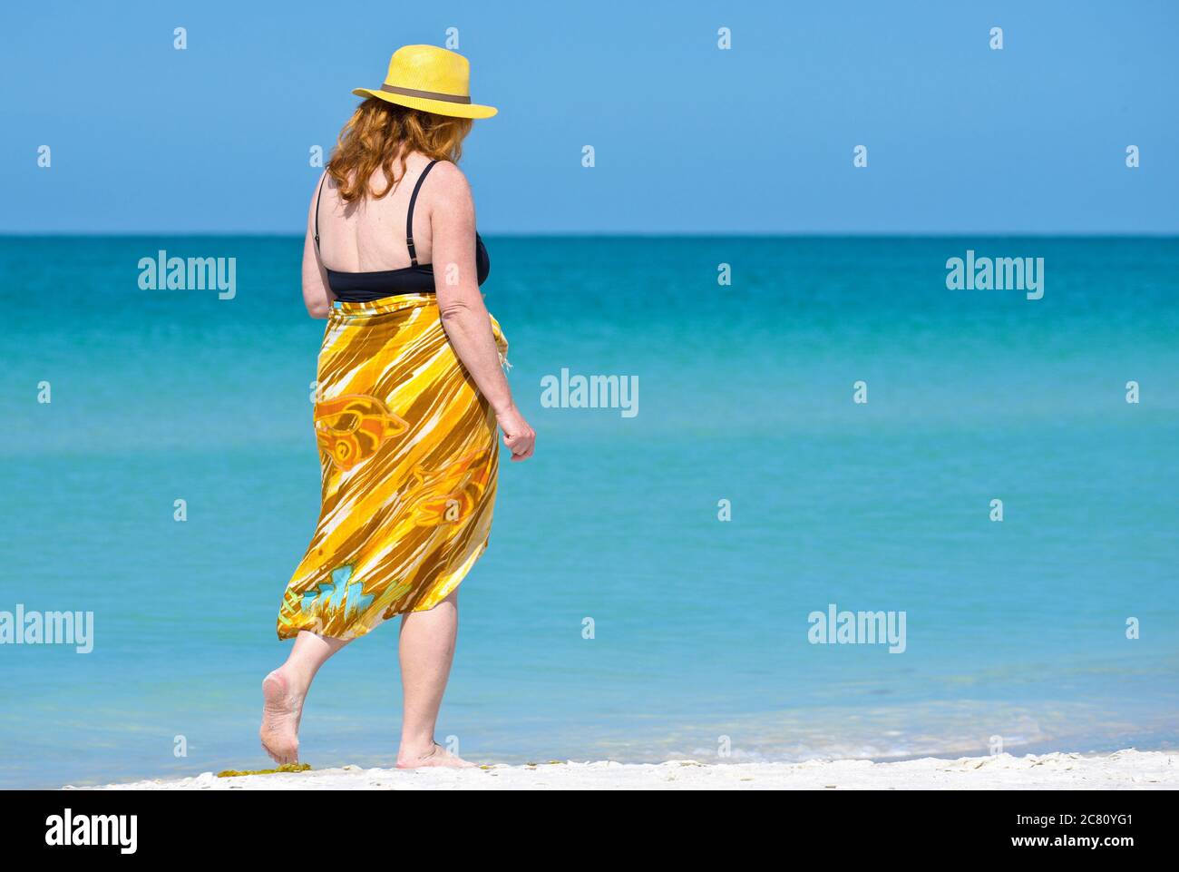 HOLMES BEACH, ANNA MARIA ISLAND, FL / USA - 1. Mai 2018: Schöne reife Frau bei einem Spaziergang am Strand und einem schönen Sommertag. Stockfoto