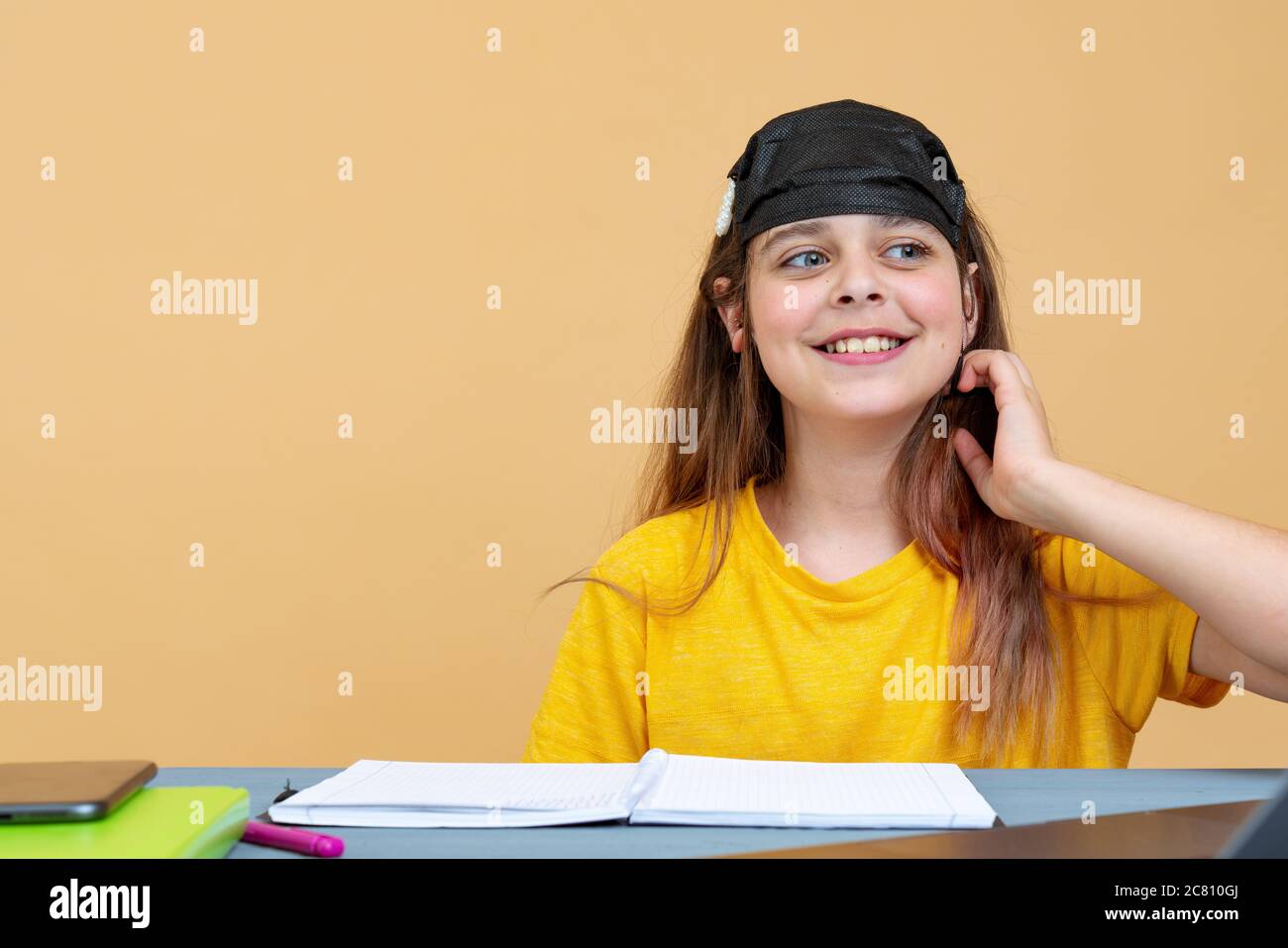 Mädchen in einer schwarzen Maske auf dem Kopf arbeitet isoliert auf einem Laptop zu Hause. Arbeiten Sie am Remote-Zugriff. Selbstisolierung Stockfoto