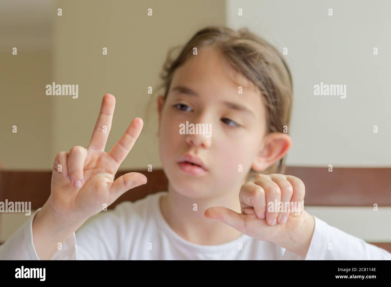 Grundschülerin macht ihre Hausaufgaben. Sie macht ihre eigenen Hausaufgaben allein zu Hause, weil die Schulen wegen der Corona pandemi geschlossen sind Stockfoto