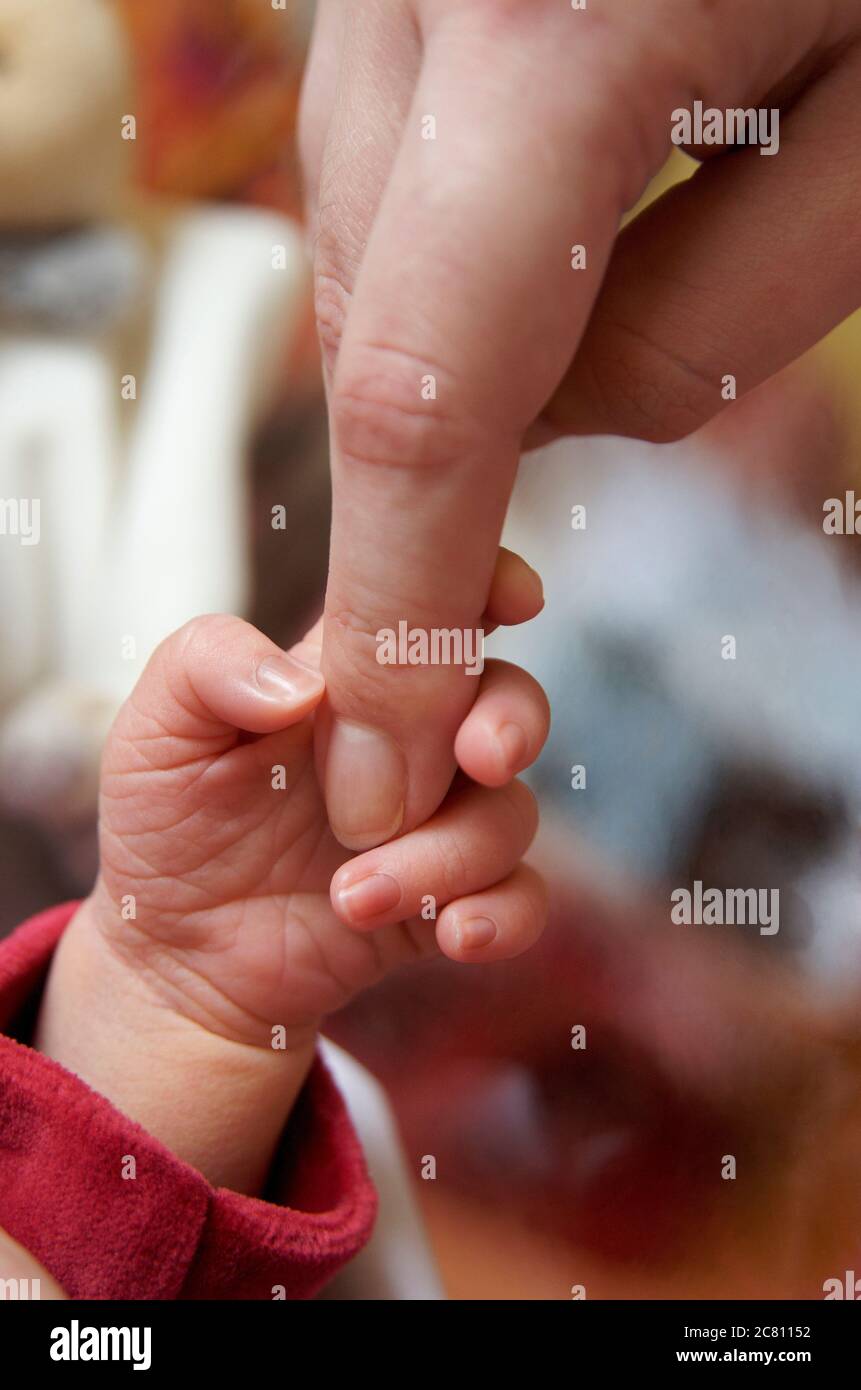 Baby hält den Finger einer Mutter Stockfoto