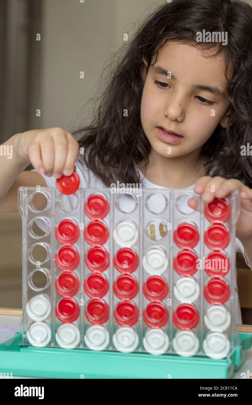 Sie spielt mit Brettspiel ist verbinden 4. Schwarze Haare Mädchen spielen Brettspiel verbinden 4 rot und weiß Stockfoto