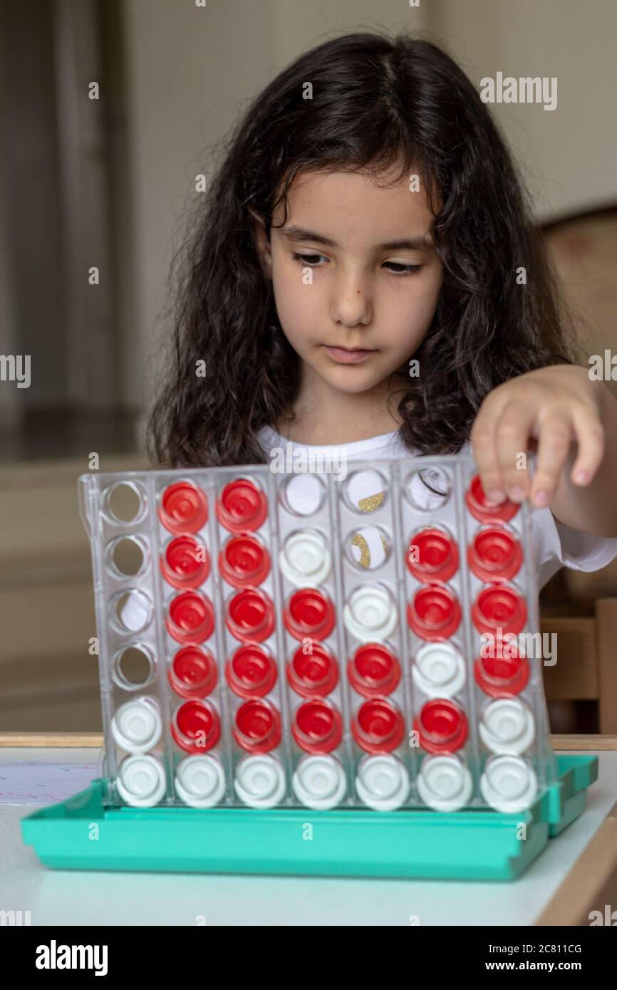Sie spielt mit Brettspiel ist verbinden 4. Schwarze Haare Mädchen spielen Brettspiel verbinden 4 rot und weiß Stockfoto