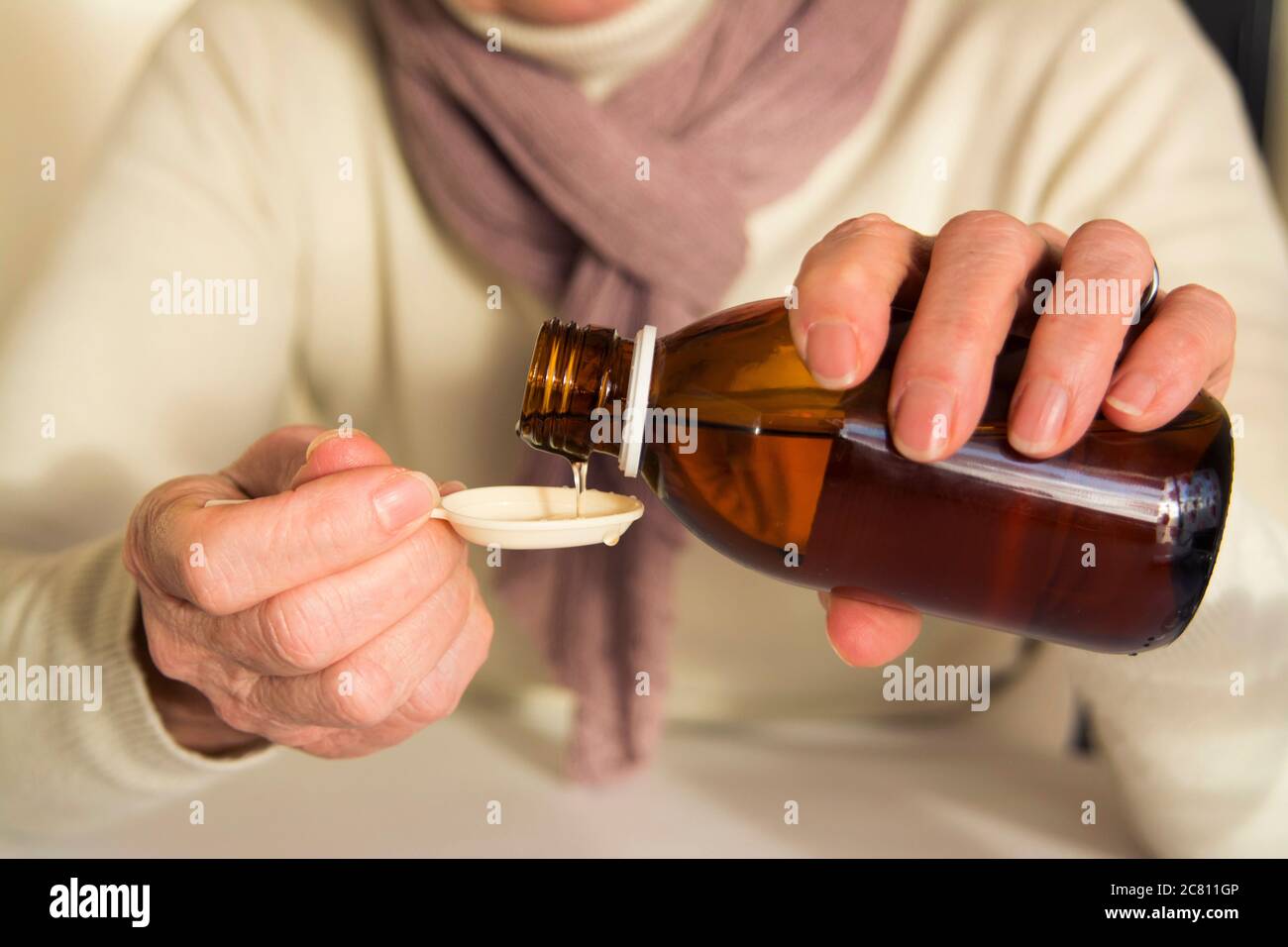 Person, die im Winter Sirup in einen Löffel gießt Stockfoto