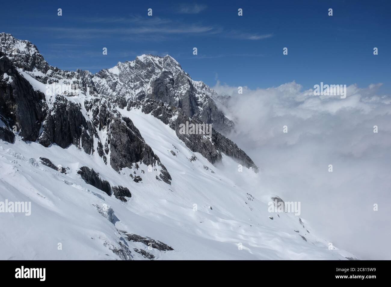Weißer Schneehang des Jadedrachen-Schneebergs in der Provinz China Yunnan. Weiße Wolken Stockfoto