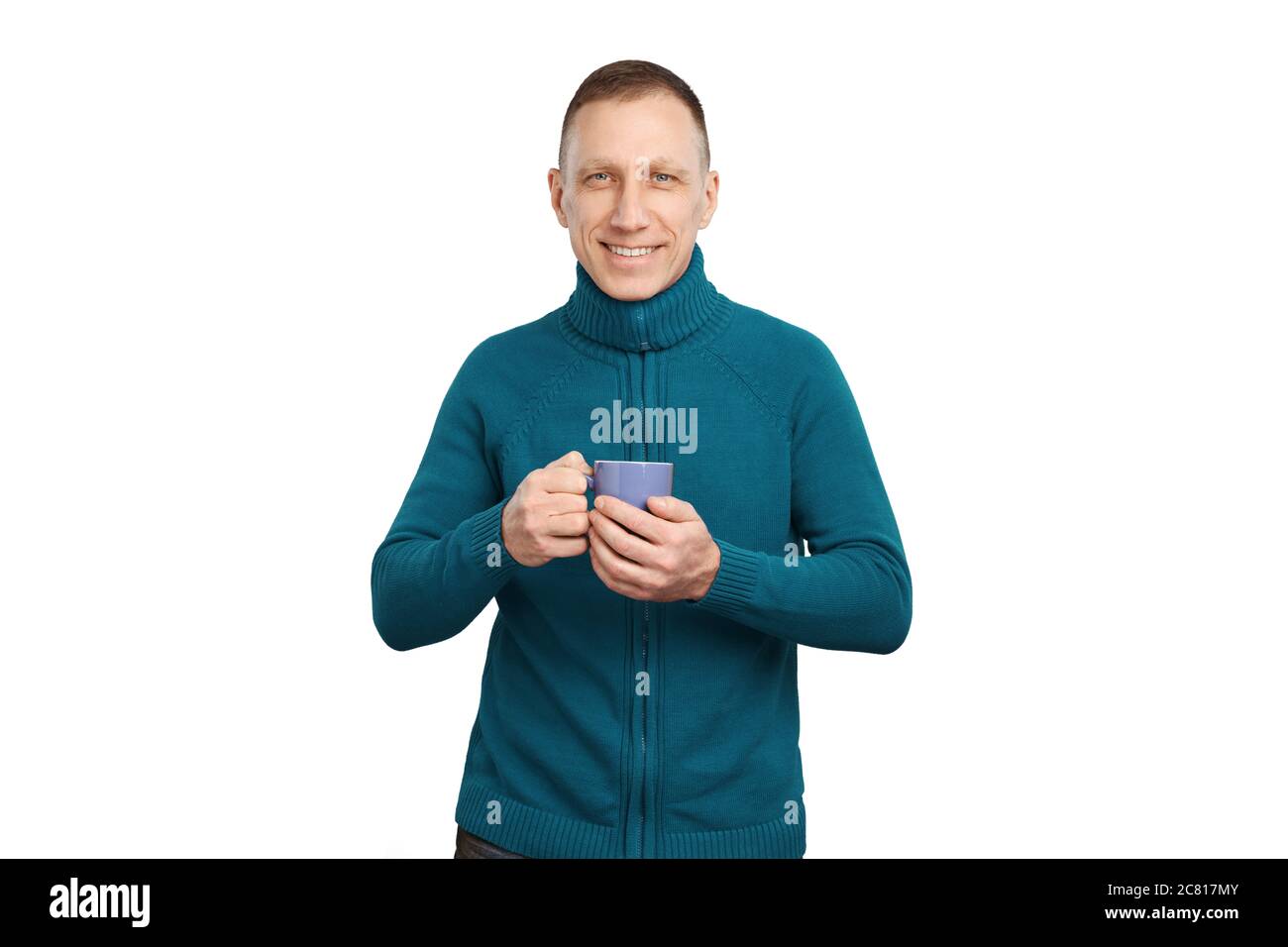 Lächelnder Mann im mittleren Alter in blauem Pullover isoliert auf weißem Hintergrund hält eine blaue Tasse Kaffee. Stockfoto