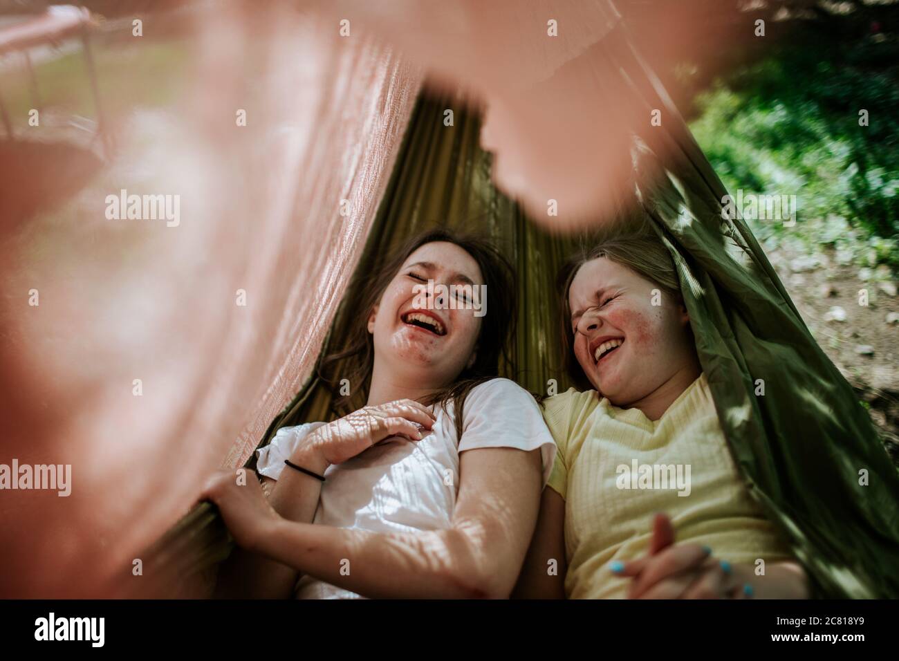 Junge Mädchen lachen und kichern in der Hängematte Stockfoto