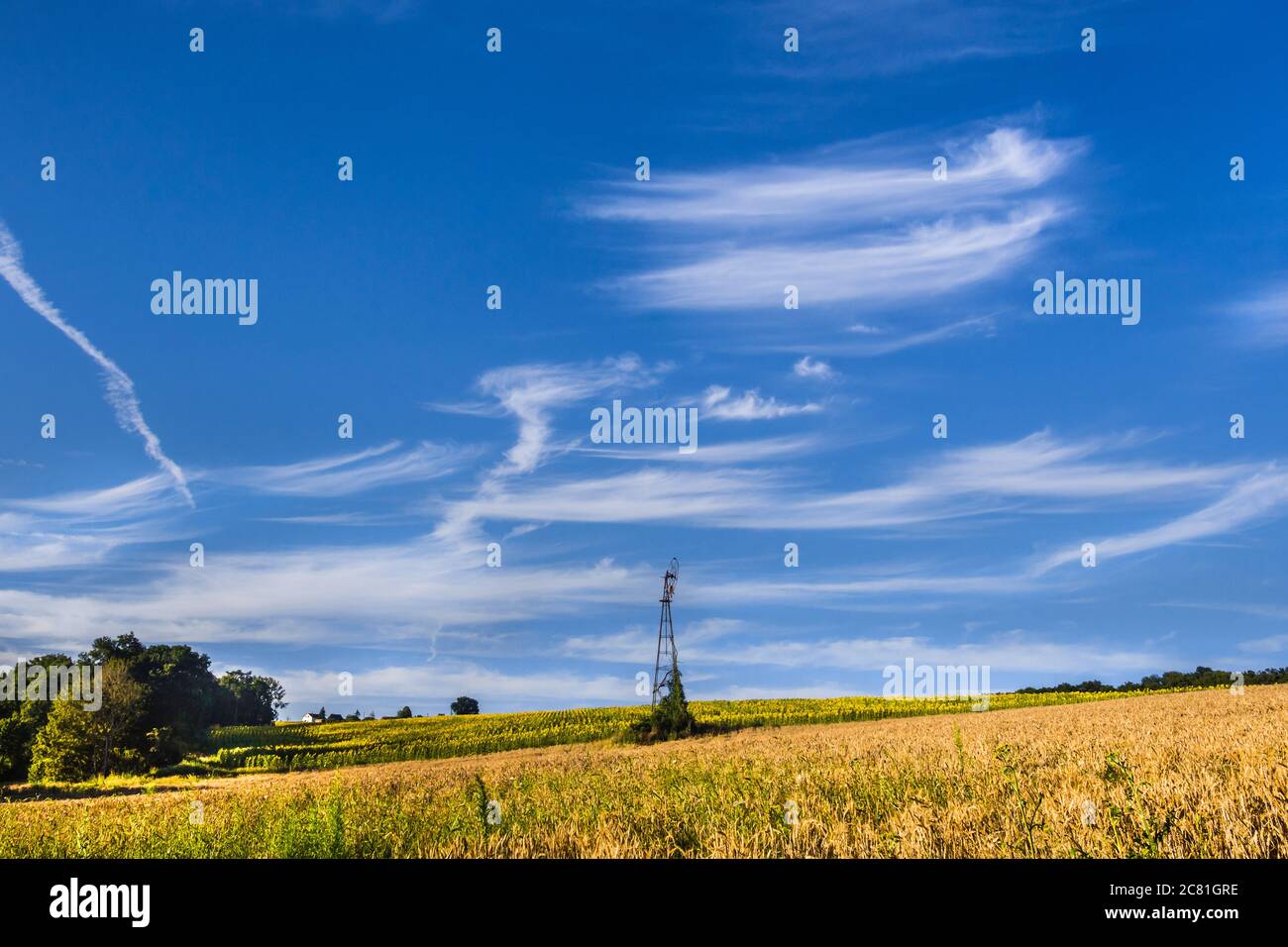 Französisches Ackerland mit alter Wasserpumpe unter blauem Himmel und Zirruswolken. Stockfoto