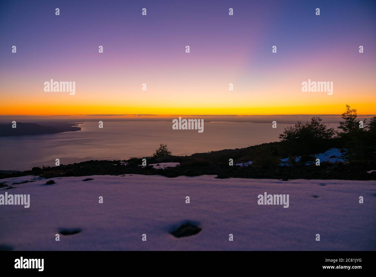 Lichtstrahlen kreuzen den Himmel mit schönen Farben, nach Sonnenuntergang in den verschneiten Bergen Stockfoto