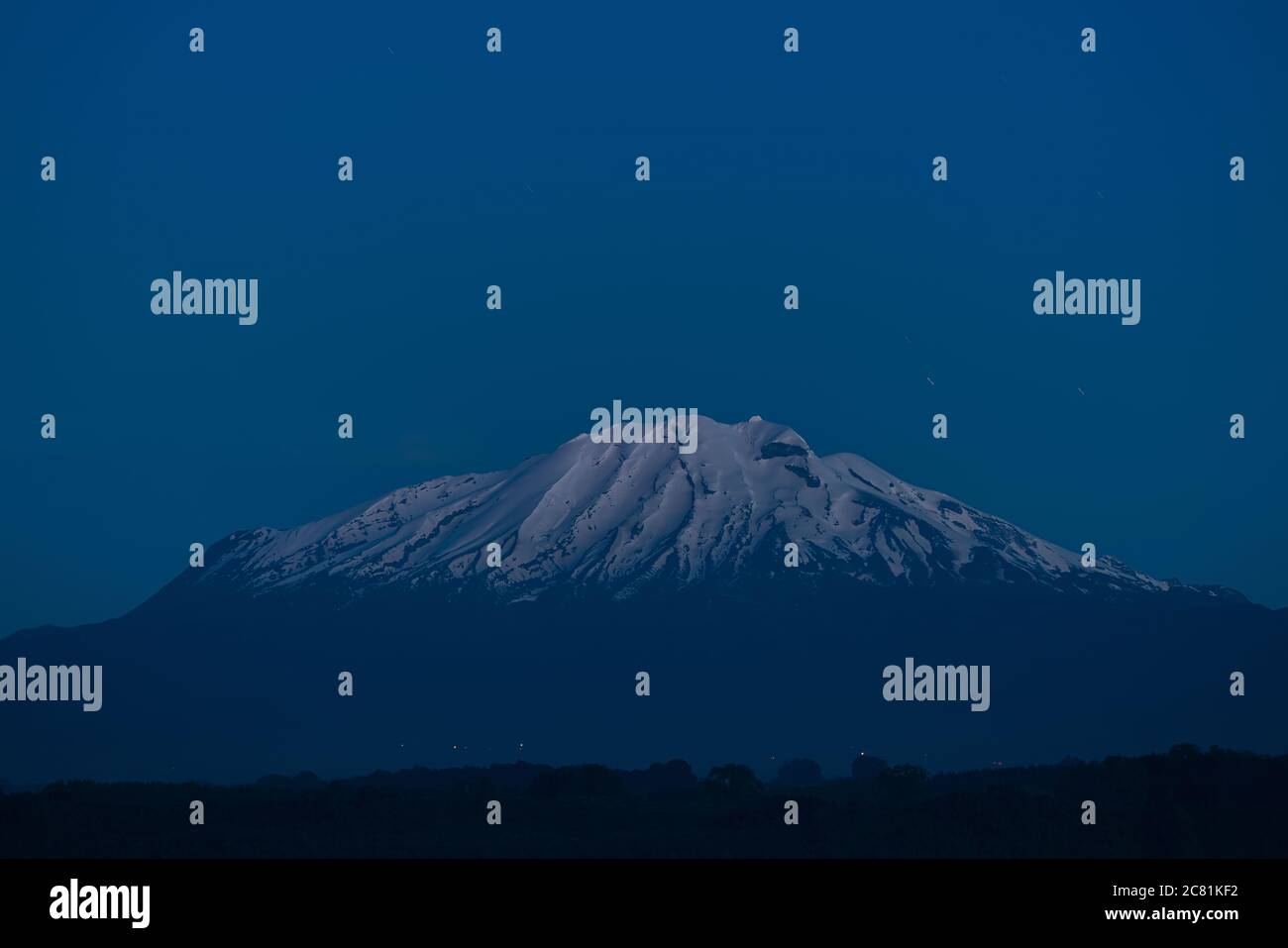 Calbuco Vulkan mit Licht vom Beginn der astronomischen Stunde, bewegte Sterne im Hintergrund Stockfoto