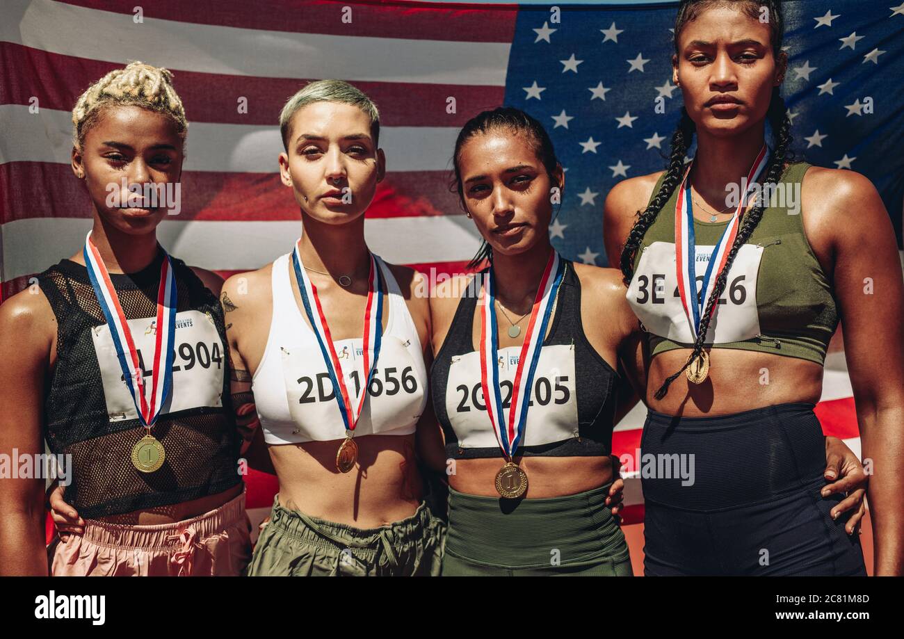 Porträt von vier Athleten mit Goldmedaillen vor der Flagge der USA. Diverse Sportlerinnen nach dem Sieg. Stockfoto