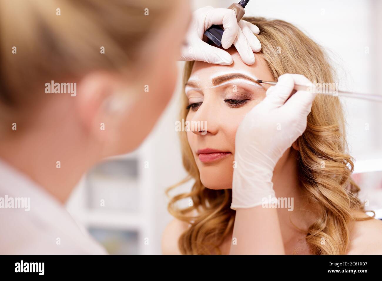 Make-up und Beauty-Konzept - Nahaufnahme von Make-up Künstler Malerei Augenbrauen im Beauty-Studio Stockfoto
