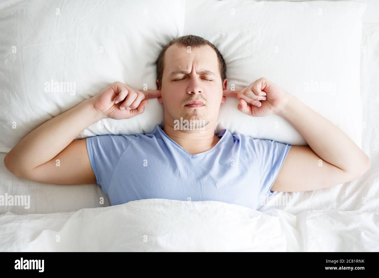 Laute Nachbarn Und Kopfschmerzen Schlafriger Mude Junger Mann Der Im Bett Liegt Und Die Ohren Mit Den Fingern Bedeckt Die Vor Larm Schutzen Stockfotografie Alamy