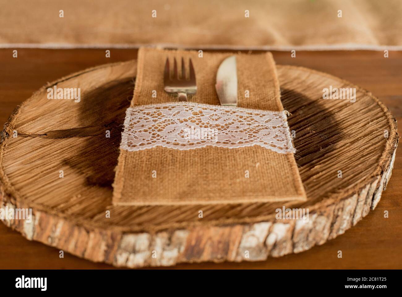 Nahaufnahme einer Gabel und eines Messers in Leinen Tasche auf einem Holzteller auf dem Tisch Stockfoto