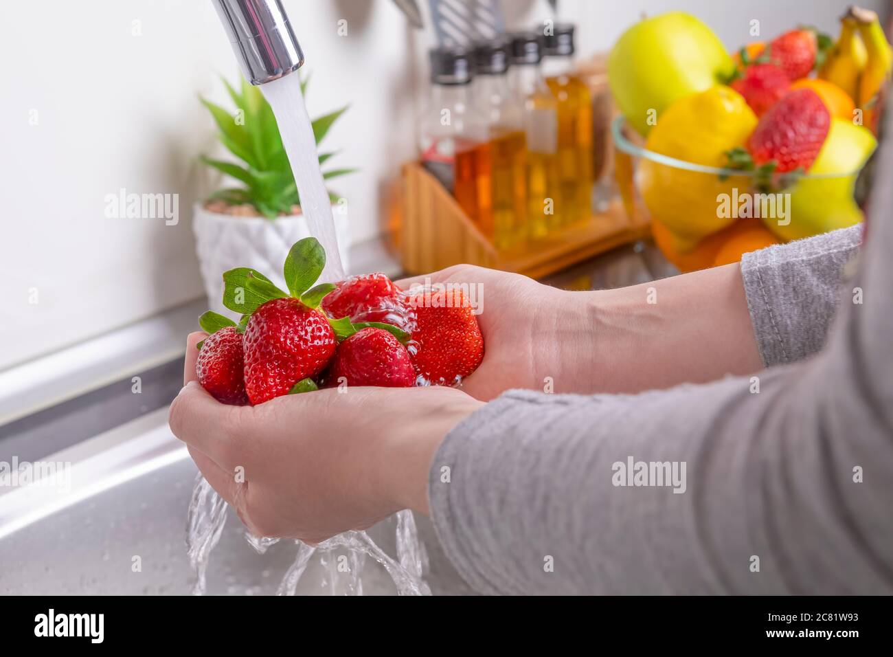 Frau Hände waschen Erdbeeren in der Küche. Essen frische und gesunde Früchte Konzept. Nahaufnahme Stockfoto