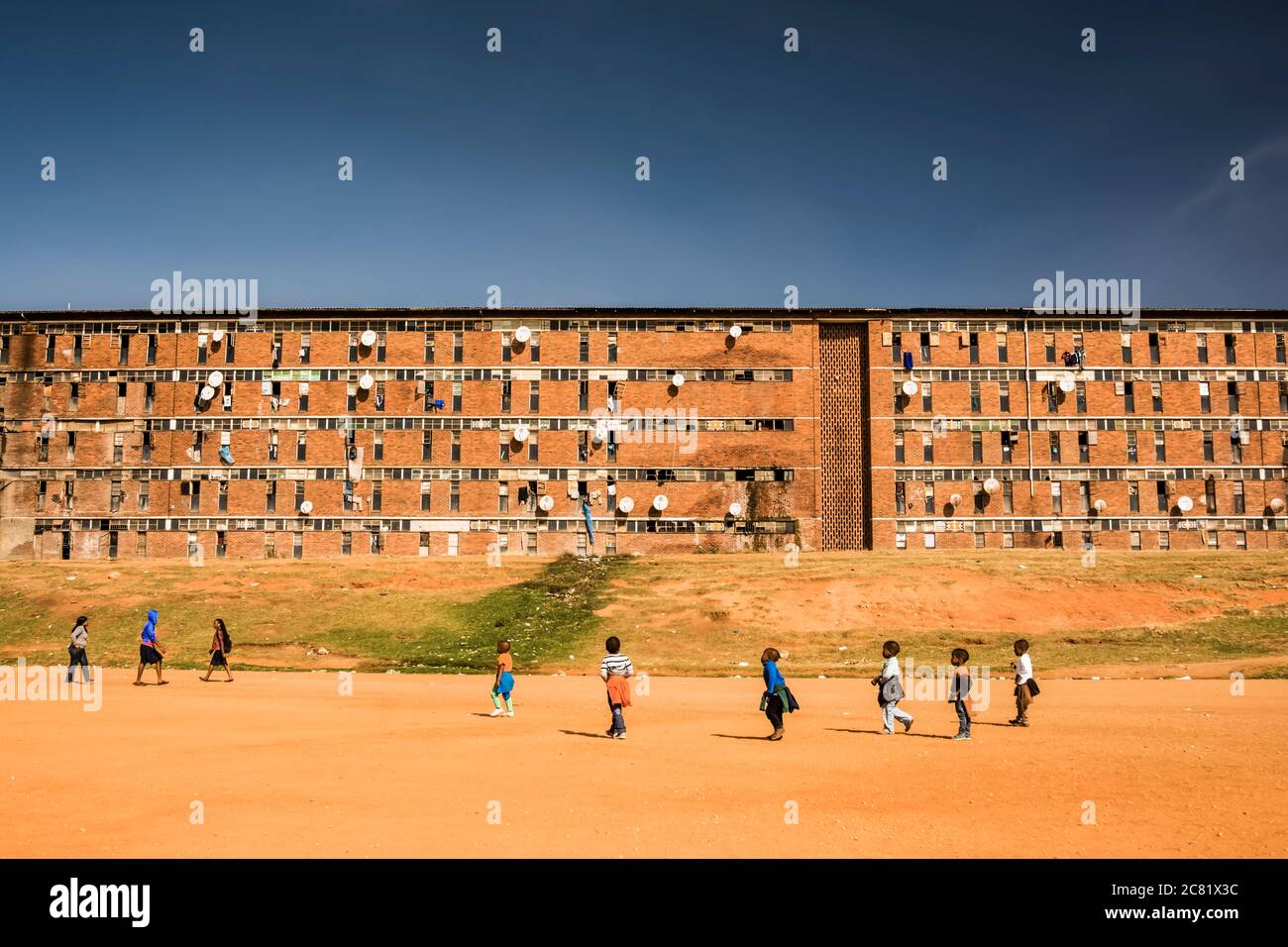 Kinder spielen vor einer Arbeiterherberge in Alexandra Township; Johannesburg, Gauteng, Südafrika Stockfoto