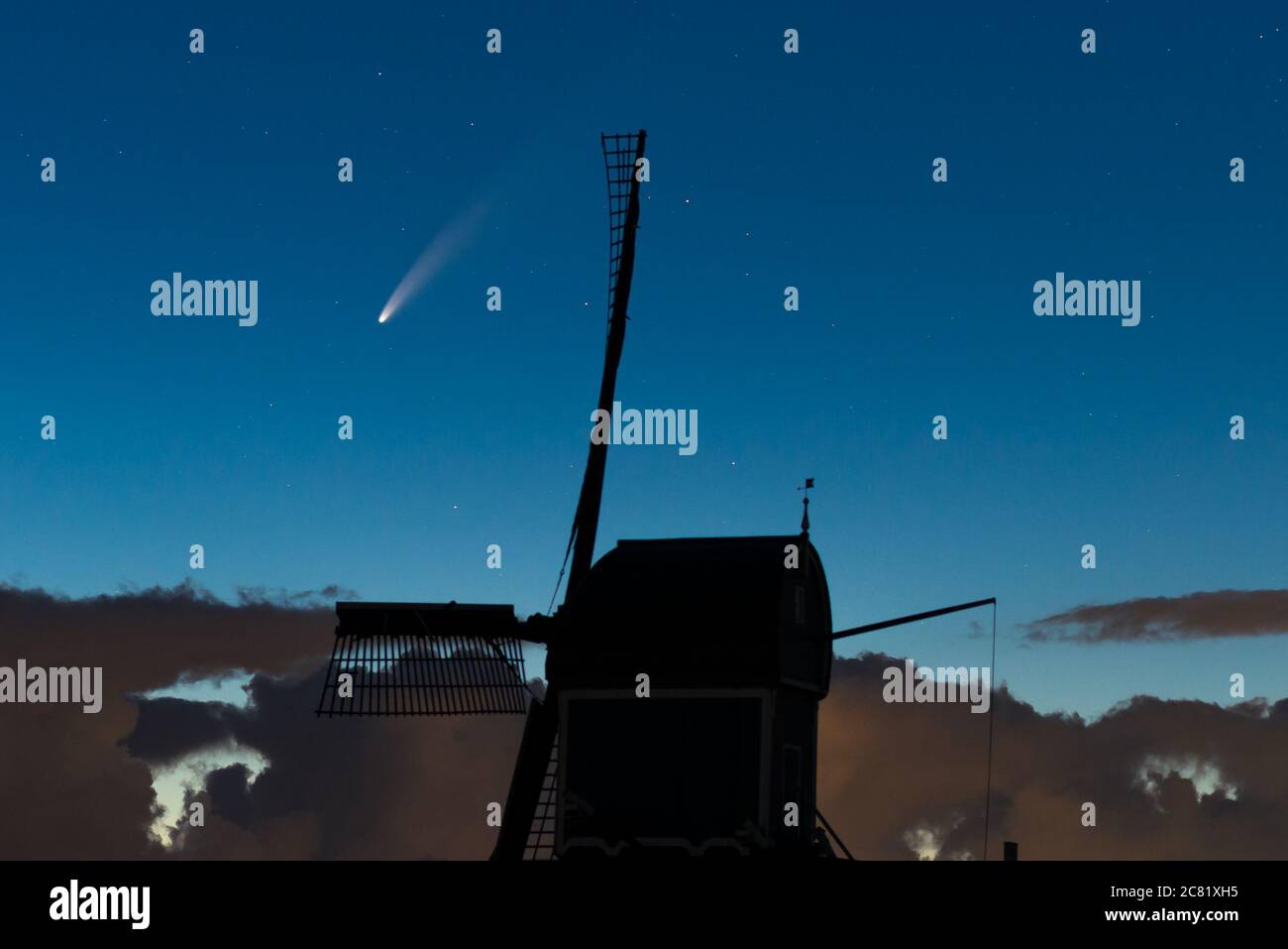 Atemberaubendes Weltraumbild, wo der Komet 'Neowise' nachts den Himmel überquert. Eine traditionelle holländische Windmühle ist gegen den Mittsommernachthimmel silhouettiert. Stockfoto