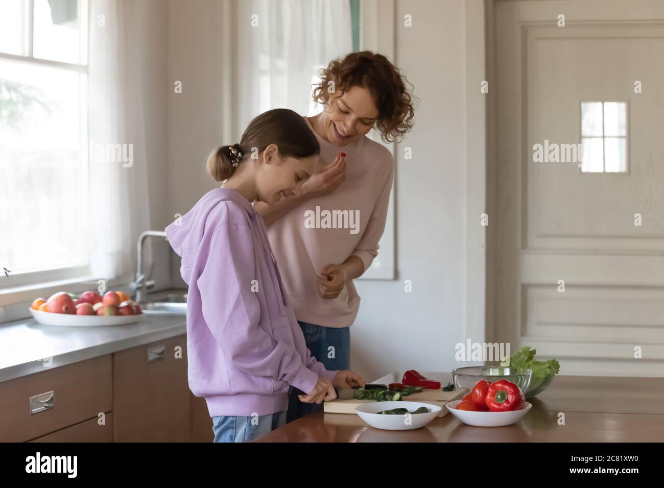 Glückliche Mutter und Teenager Tochter kochen Salat zu Hause zusammen Stockfoto