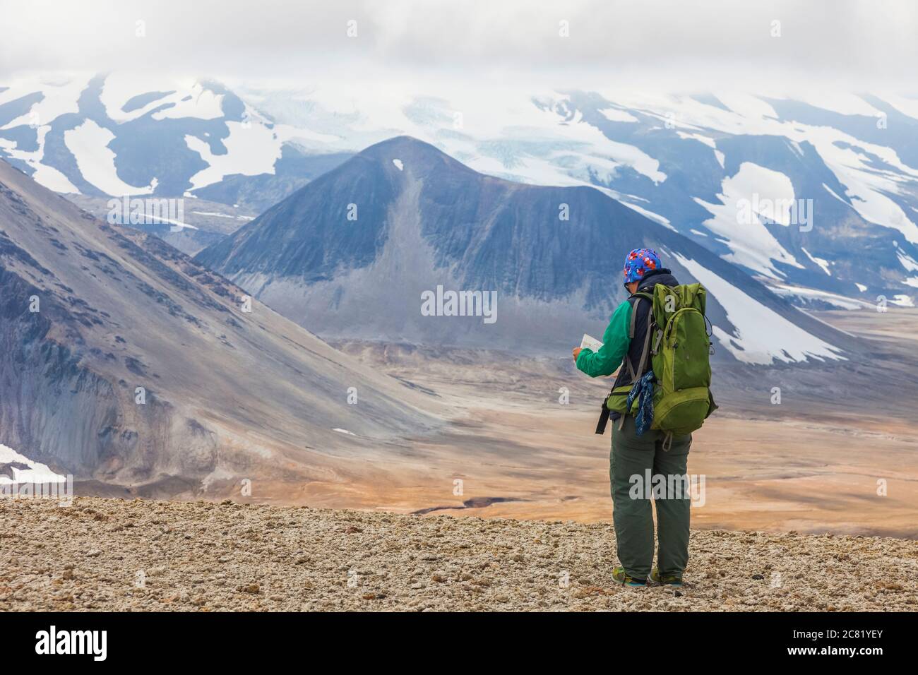 Frau, die mit dem Rucksack unterwegs ist und die Karte mit Mount Katmai im Hintergrund, Valley of Tenthousand Smokes, Katmai National Park and Preserve, Southwest Alaska Stockfoto