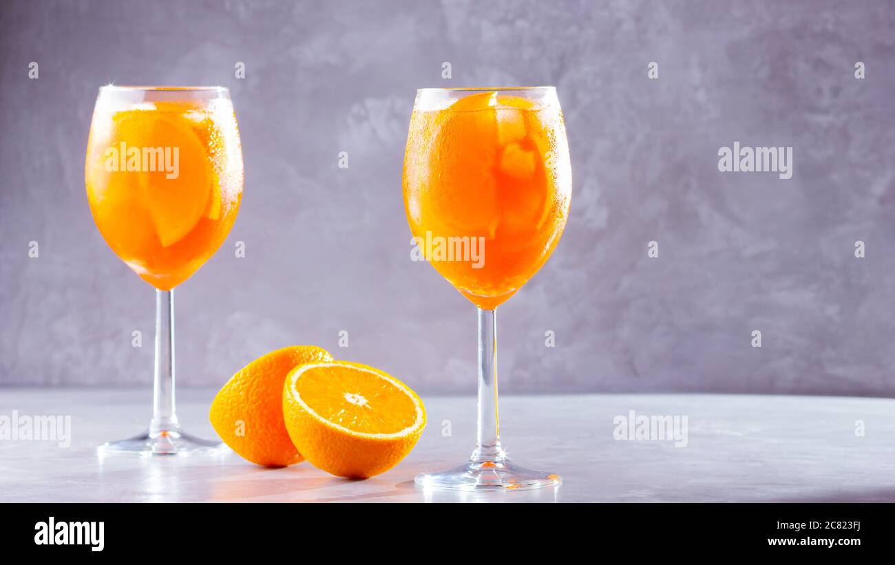 Aperol Spritz Cocktail auf grauem Hintergrund. Zwei Gläser aperol Spritz mit orangen Scheiben. Sommer italienischer Cocktail in Glas. Speicherplatz kopieren Stockfoto