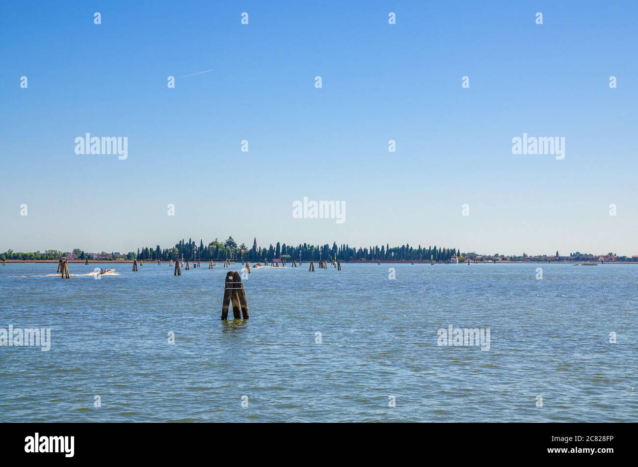 Panoramablick auf die Insel San Francesco del Deserto im venezianischen Lagunenwasser mit Holzmasten. Blick von der Insel Burano. Provinz Venedig, Region Venetien, Norditalien Stockfoto