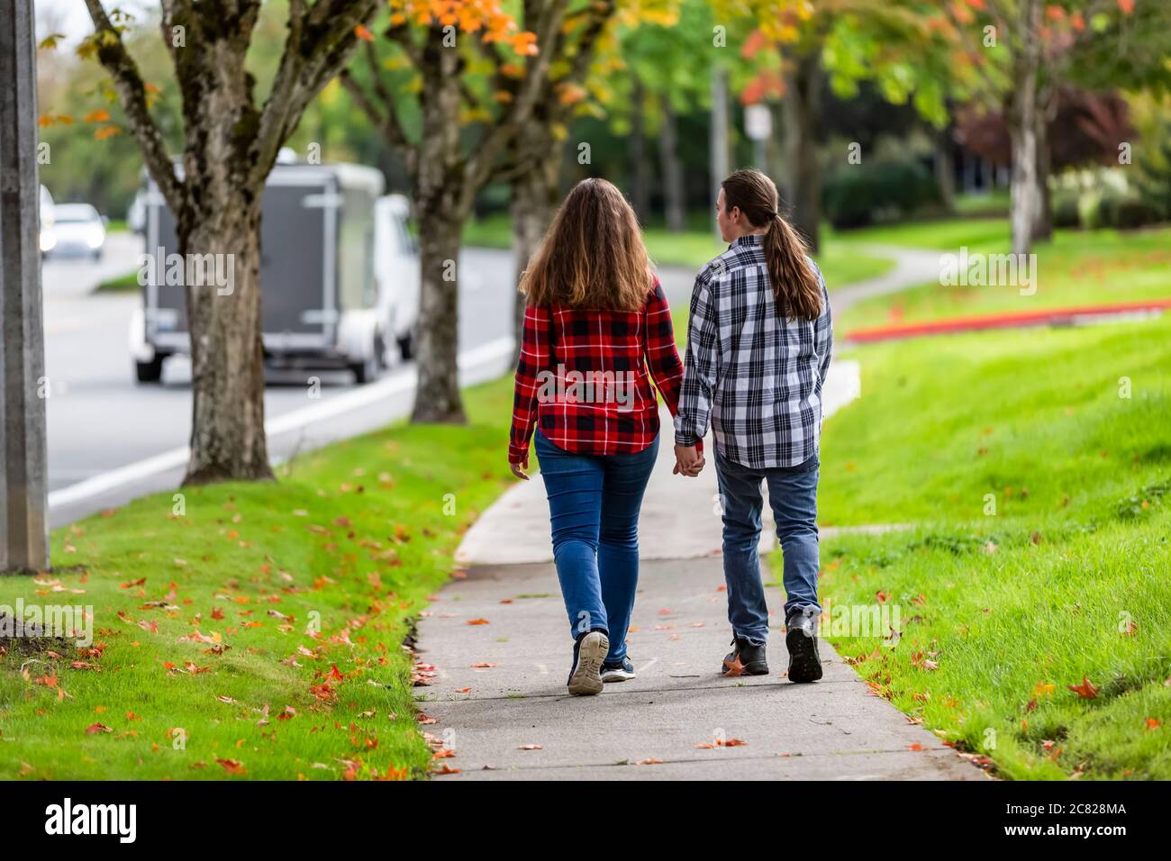 Ein Junge und ein Mädchen im Teenageralter, die einen Bürgersteig mit Händen hinuntergehen; Bothell, Washington, Vereinigte Staaten von Amerika Stockfoto