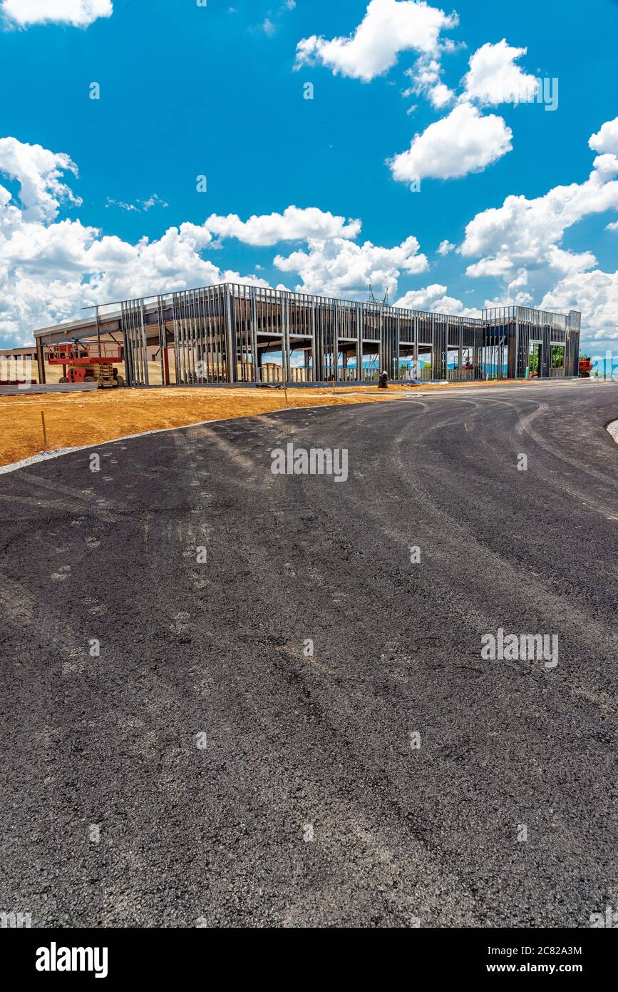 Vertikale Aufnahme einer frischen, auf einer schwarzen Spitze verlaufenden Straße, die zu einer kommerziellen Baustelle führt. Stockfoto