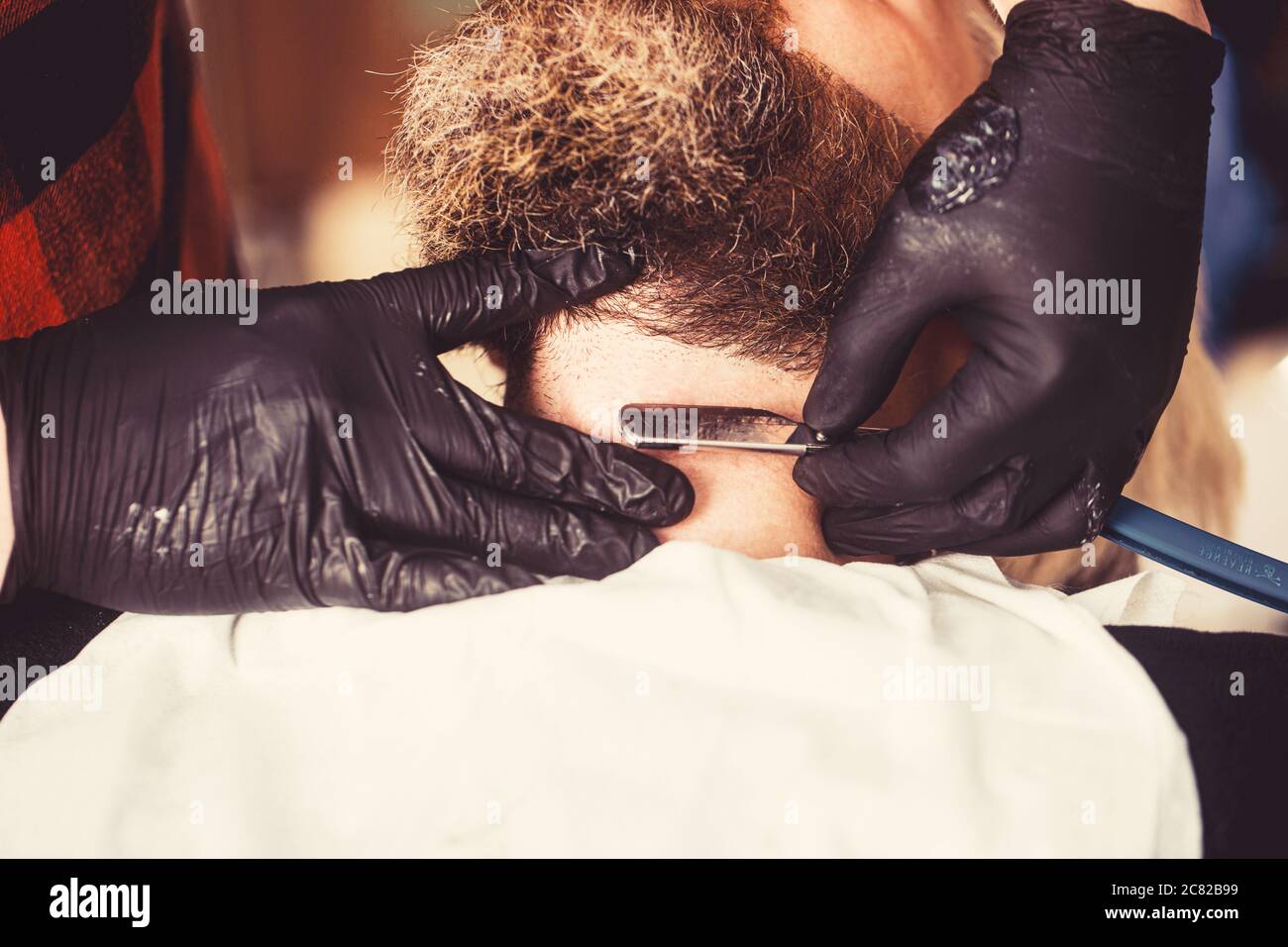 Nahaufnahme der Seite des jungen bärtigen Mannes, der sich im Friseursalon einen Bartschnitt vom Friseur erhaart. Perfekte Form. Stockfoto