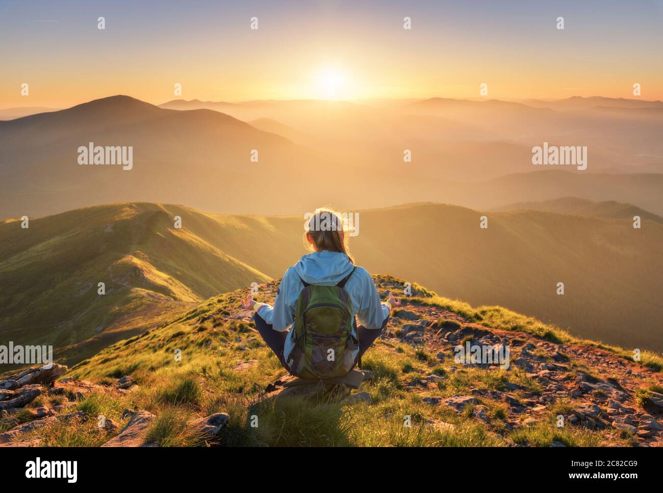 Junge Frau mit Rucksack auf dem Berggipfel sitzen Stockfoto