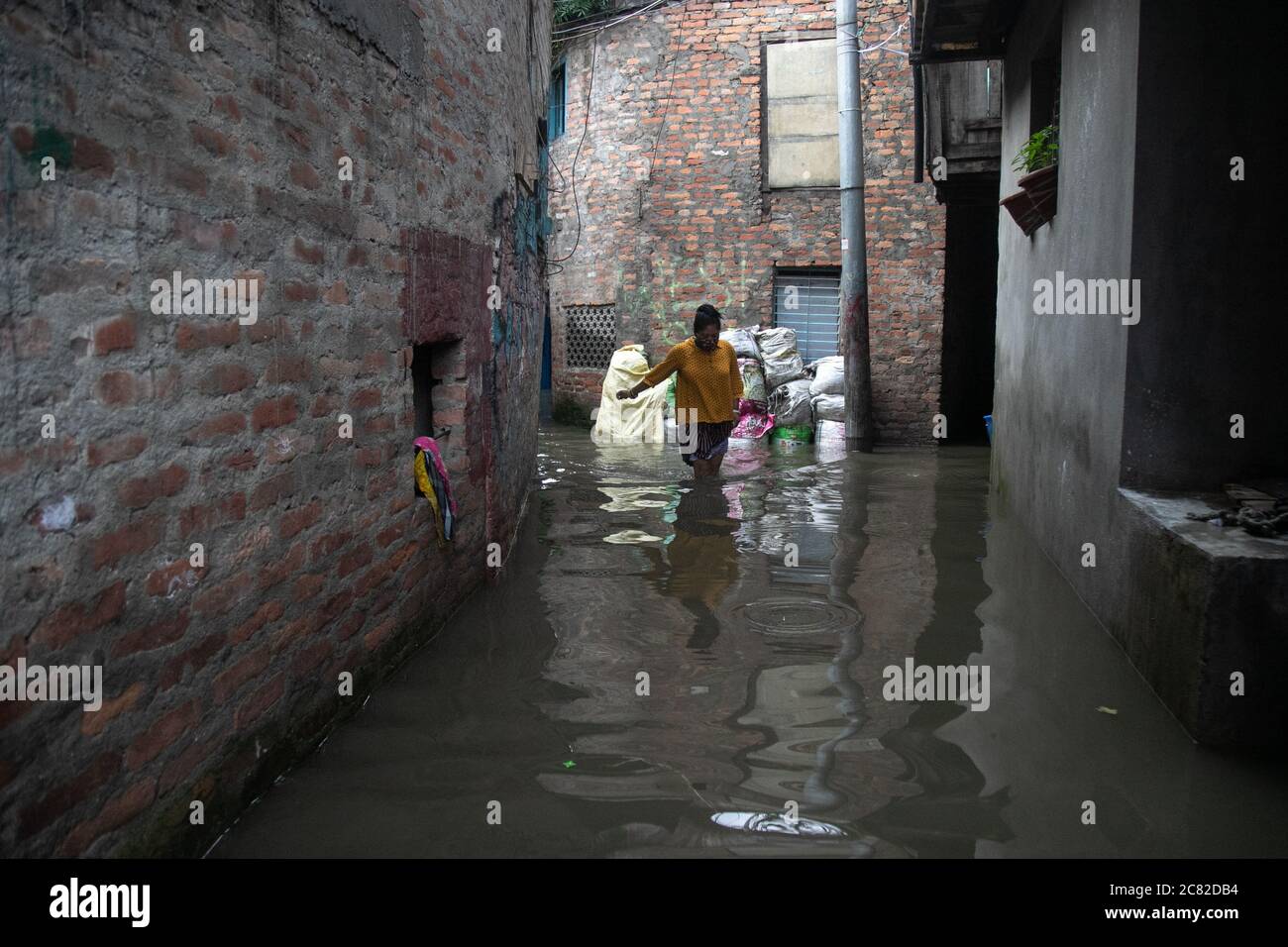 Eine Frau geht durch eine Gasse, während der Fluss durch die ständigen Regenfälle in einem Slum am Ufer des Bagmati Flusses in Kathmandu überfließt.die durch den Monsun verursachten Katastrophen haben am Montag 114 Menschenleben gefordert, während Hunderte von Haushalten im ganzen Land vertrieben wurden. Mehrere von Katastrophen heimgesucht Gebiete wurden abgeschnitten, wie Überschwemmungen und Erdrutsche haben weg Brücken und Straßenabschnitte auf einigen Autobahnen. Stockfoto