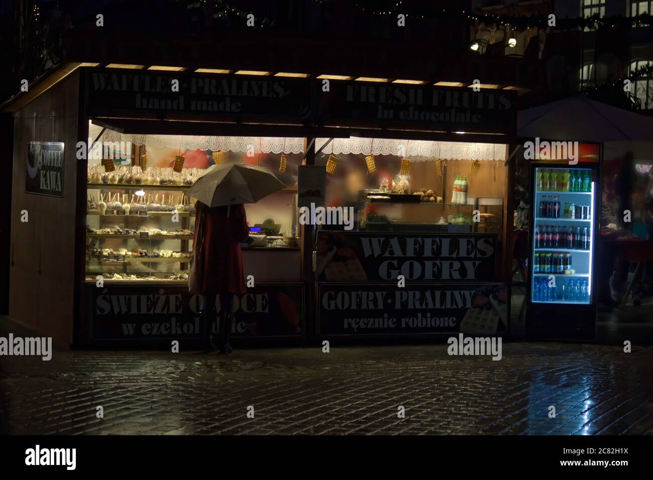 Krakau, Polen - 22. Dezember 2014: Rückansicht einer Frau in Winterjacke, die während Weihnachten einen Regenschirm vor dem Waffelgeschäft hält, sogar in der Stadt ce Stockfoto