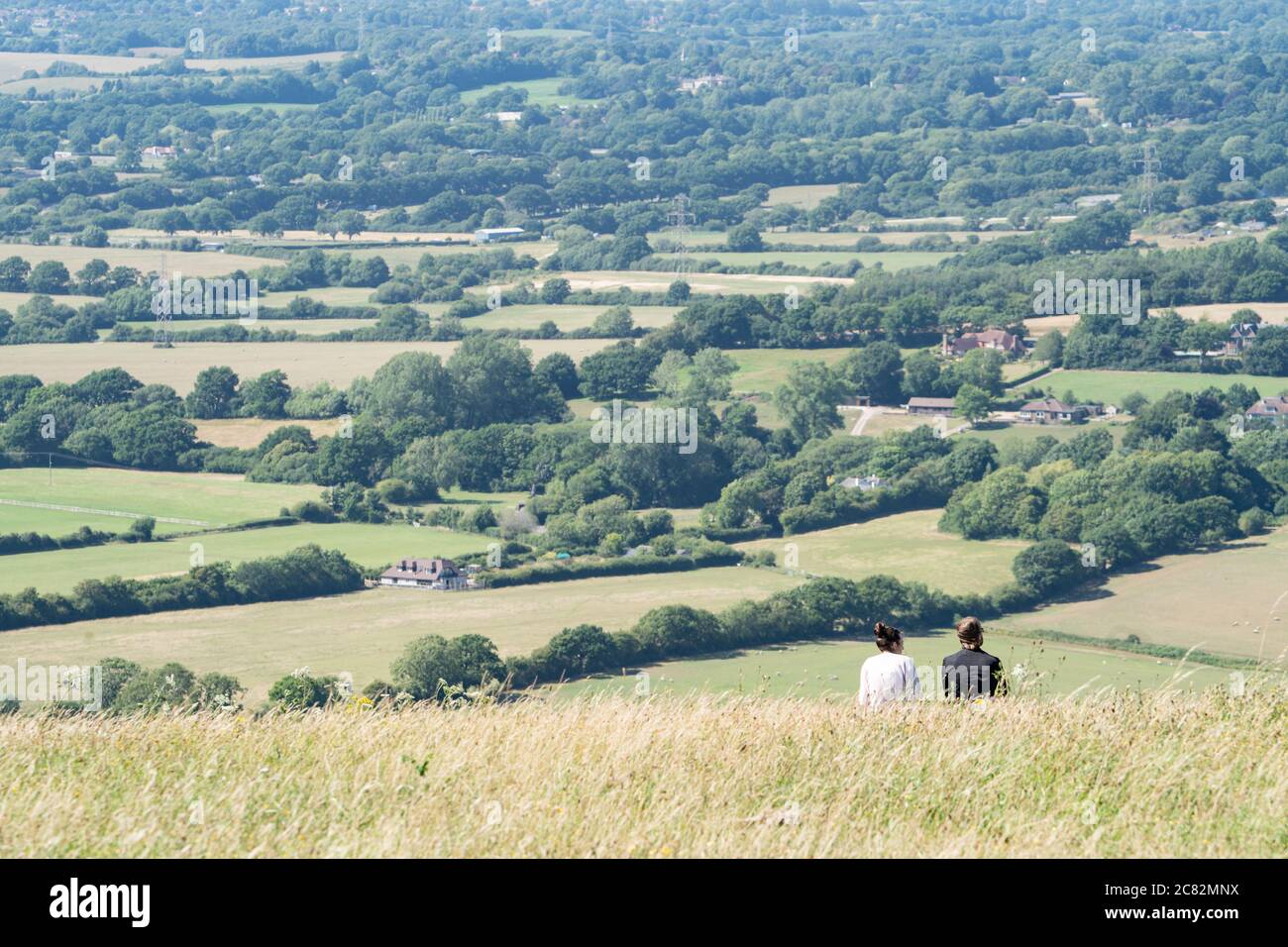 Junges Paar auf einem Hügel, das den Blick über das Devil's Deich Valley, South Downs, Sussex, Großbritannien, bewundert Stockfoto