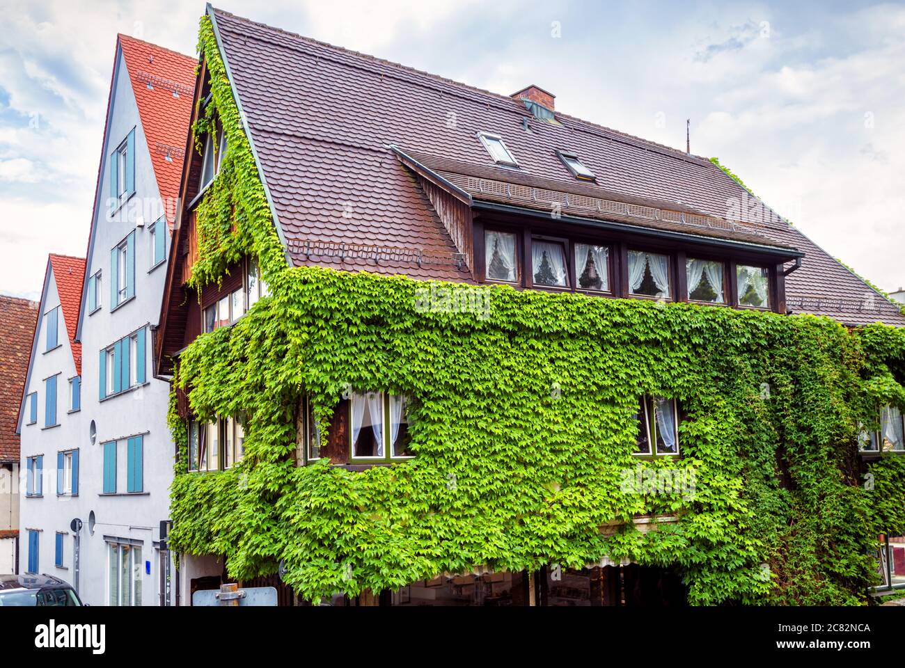 Haus bewachsen mit Efeu in der Stadt Ulm, Deutschland. Überwuchert Fassade im Sommer. Grünpflanzen auf Wohnstruktur oder Hotel, Wand mit Gemüse Stockfoto