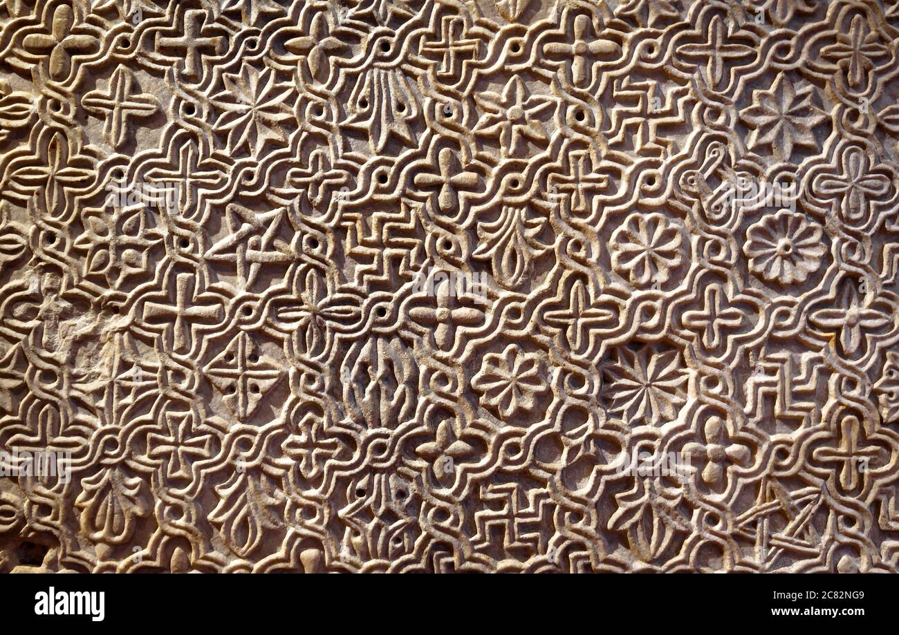 Byzantinisch gemustertes Ornament in Steinwand geschnitzt, alte Textur Hintergrund, Detail der Innenausstattung mit geometrischen Relief. Symbole Muster eingeschrieben Stockfoto