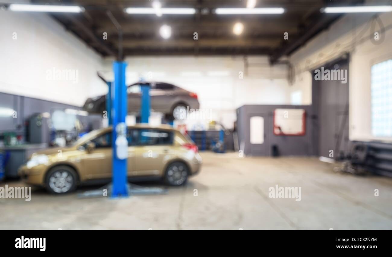 Autowerkstatt Innenraum in Bokeh, verschwommen defokussieren Hintergrund. Auto auf Lift in Mechaniker-Werkstatt oder Garage, Fahrzeuge im Inneren Wartung. Arbeitsplatz A Stockfoto