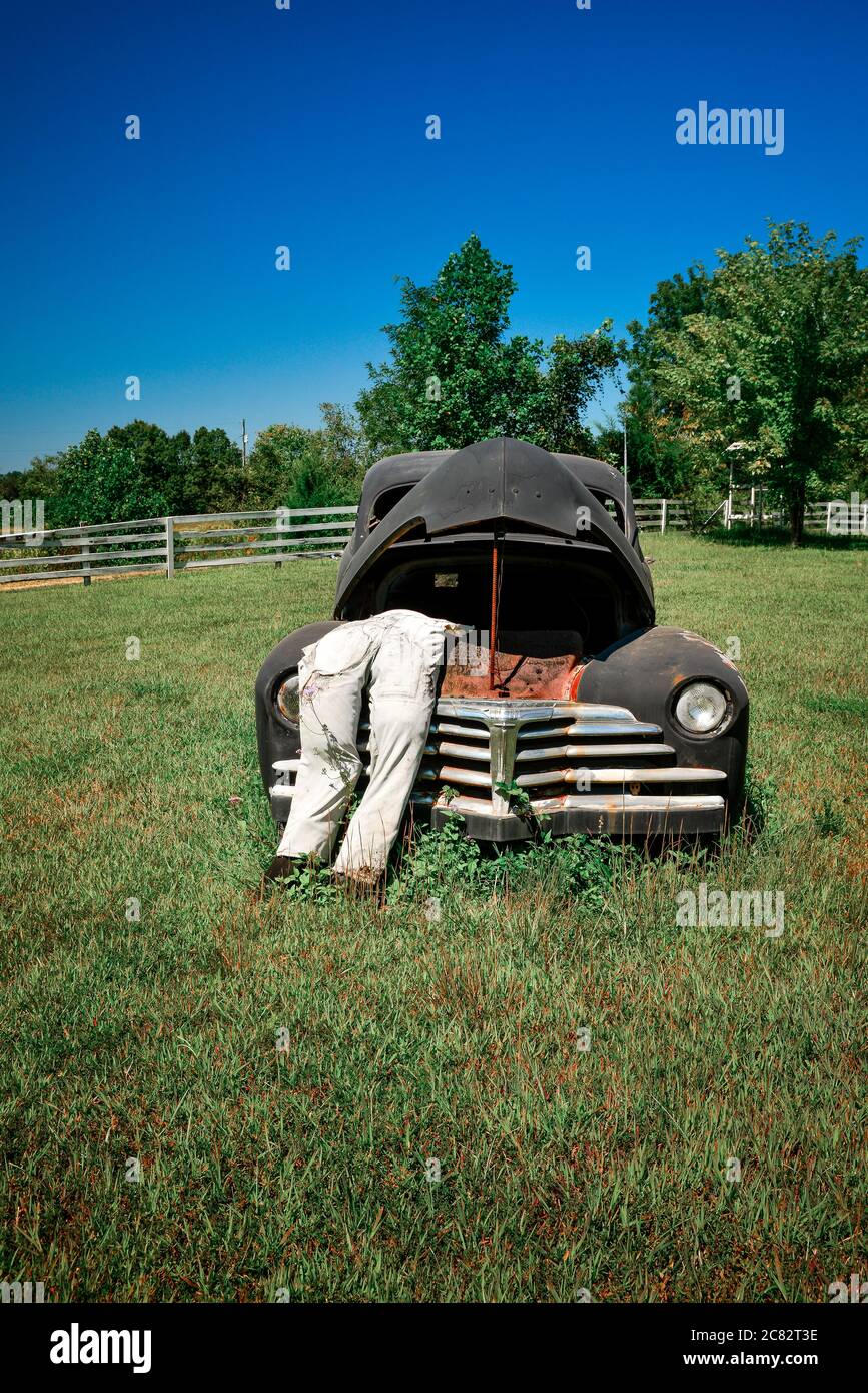 Eine gefälschte Stadtszene eines ausgestopften Dummy in Overalls lehnt sich in die poppte Kapuze auf alten 1930er-Auto in ländlichen grünen Feld in Mittel TN, USA Stockfoto