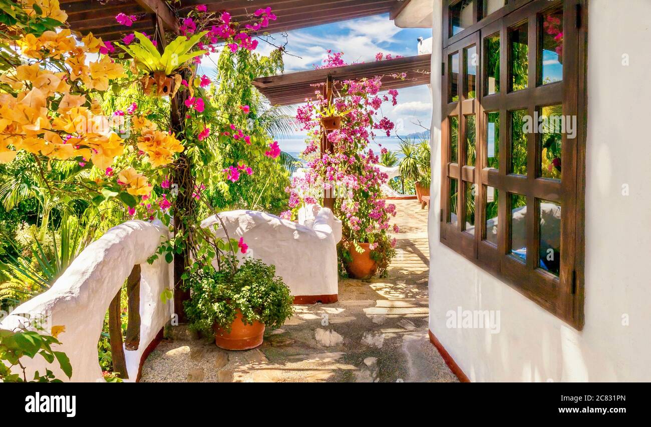 Farbenfrohe Außenansicht eines Hotelbalkens am Meer mit weißen Wänden im mediterranen Stil und lebhaften Bougainvillea-Blumen. Philippinen. Stockfoto