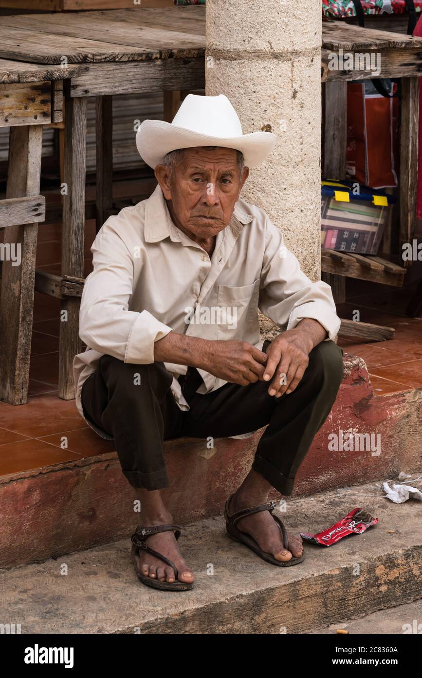 Ein älterer indigener Maya-Mann in einem Cowboy-Hut, der auf dem Markt in Muna, Yucatan, Mexiko, sitzt. Stockfoto