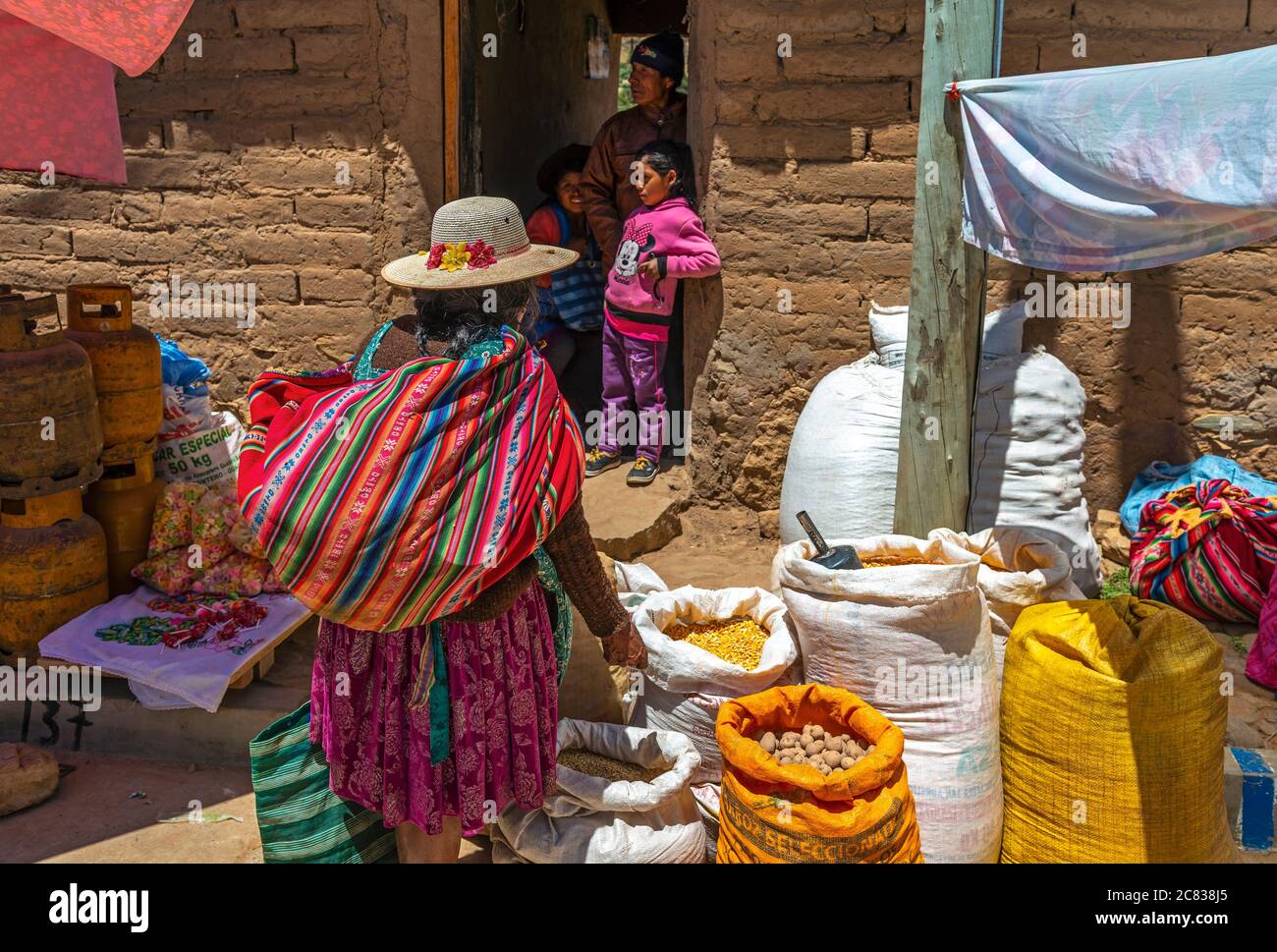 Indigene bolivianische Tarabuco Frau in traditioneller Kleidung und bunten Stoffbeutel auf dem lokalen Markt fragen nach Gemüsepreise, Sucre, Bolivien. Stockfoto