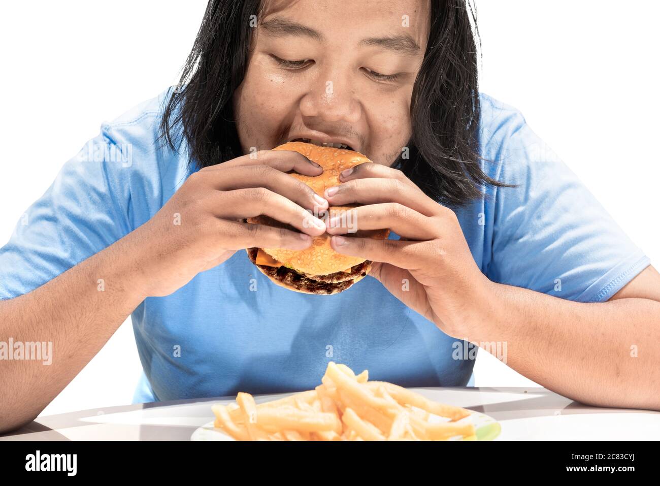 Asiatischer Mann, der einen Hamburger auf weißem Hintergrund isst Stockfoto