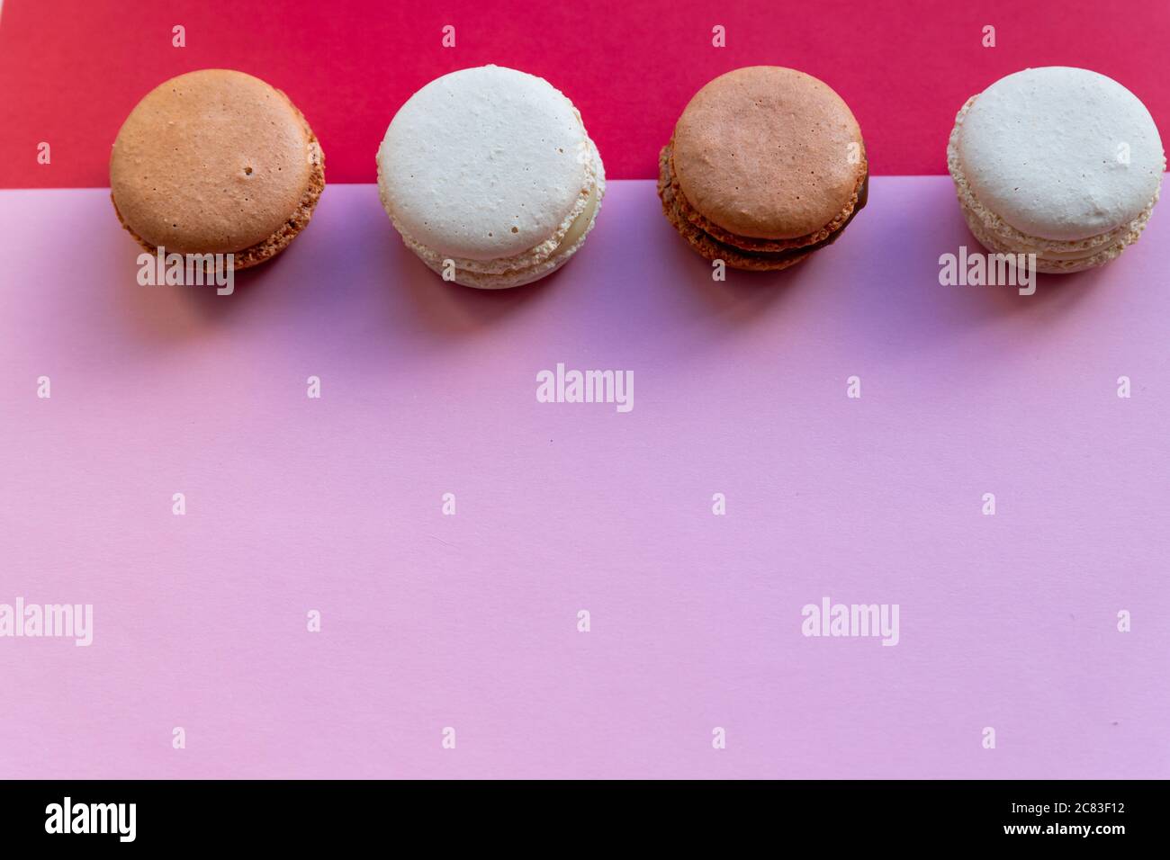 Bunte Kuchen Makronen oder Makronen, weiße Baisenkuchen auf rotem, rosa Hintergrund. Französische Mandelkekse auf Dessert Draufsicht.Französische süße Keks. Wenig Essen Stockfoto