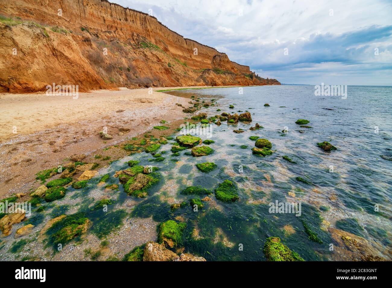 Leere Küste mit Sandsteinen und Steinen im Wasser. Wilde Küstenlandschaft Stockfoto