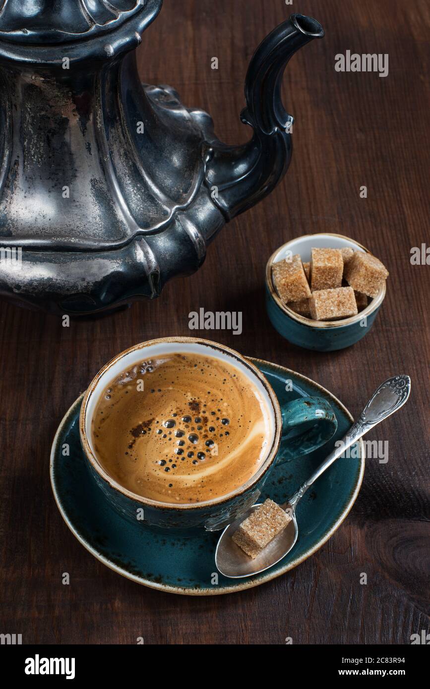 Schwarzer Kaffee in der blauen Vintage Tasse und antike silberne Kaffeekanne auf alten dunklen Holzbrettern Stockfoto