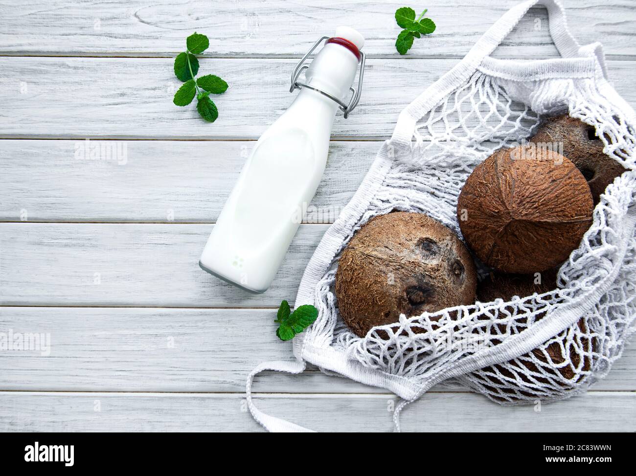 Flasche Kokosmilch und Kokosnüsse in einem Öko-Netzbeutel auf einem  Holztisch Stockfotografie - Alamy