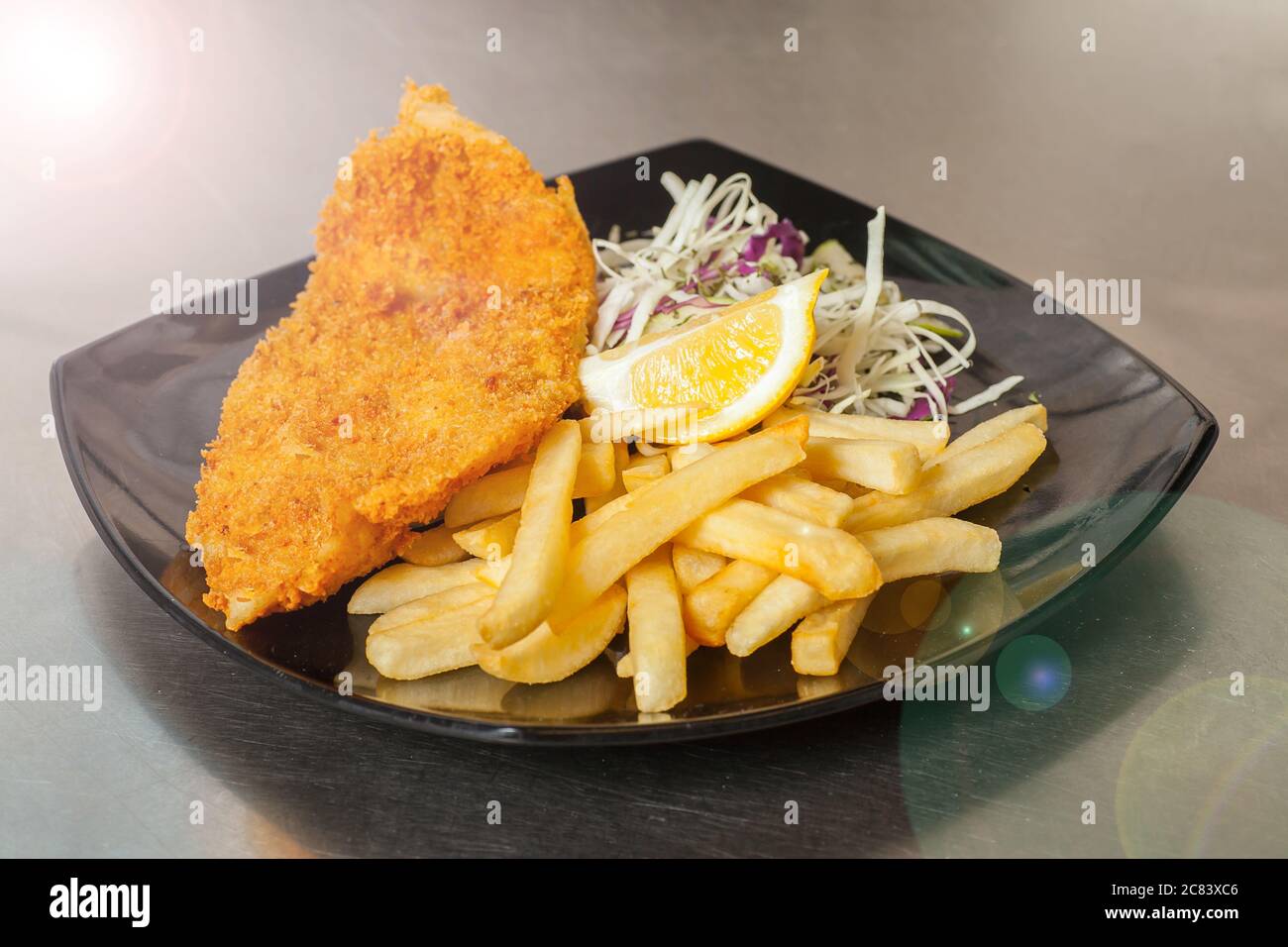 Fischfilet-Mahlzeit lag auf einem schwarzen Teller. Stockfoto
