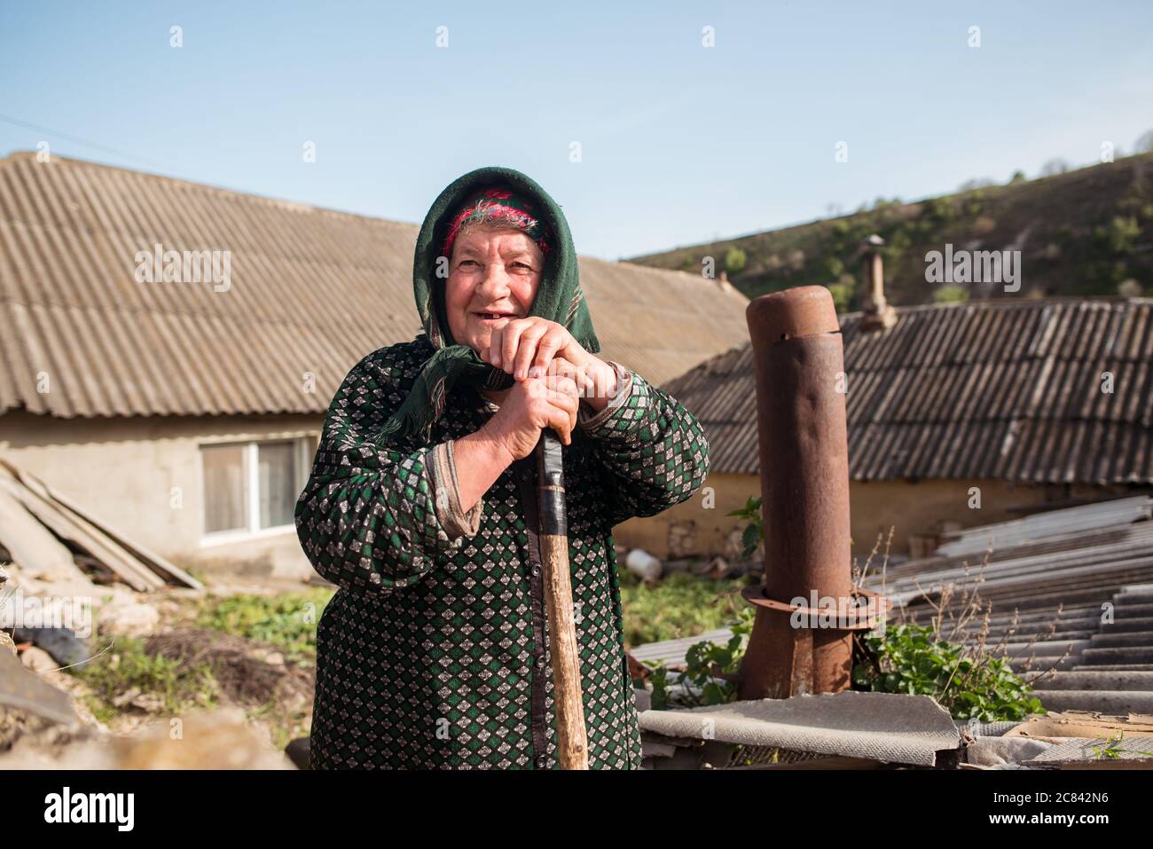 Trebujeni / Moldawien - 15. Mai 2020: Porträt einer erwachsenen moldawien Frau mit traditionellem Kopftuch, das Schaufel in ländlicher Umgebung hält Stockfoto